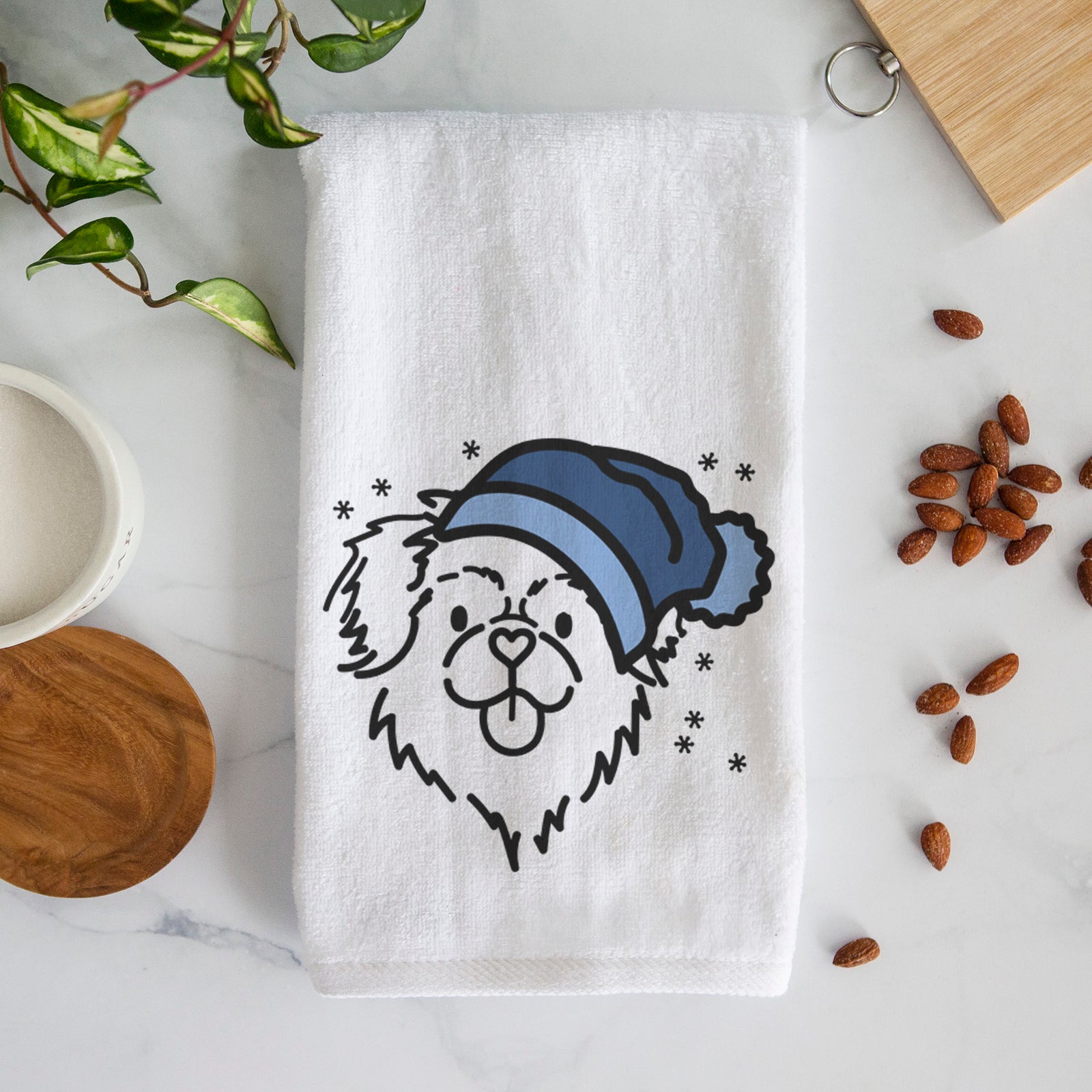 Minimalist line drawing of Jiji the Tibetan Spaniel wearing a winter beanie on a decorative hand towel