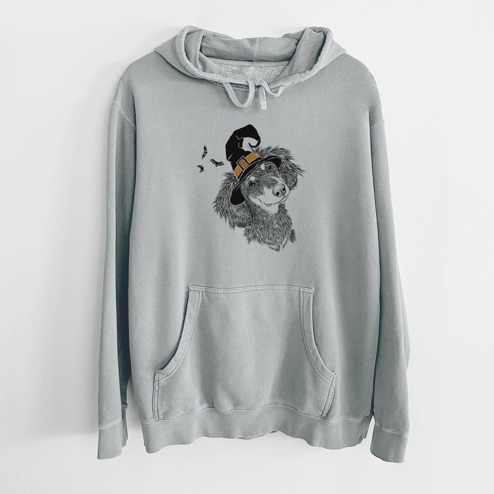 Hand-drawn sketch of Bailey the Long Haired Dachshund wearing a witch hat on a Sage Unisex pigment dyed hoodie