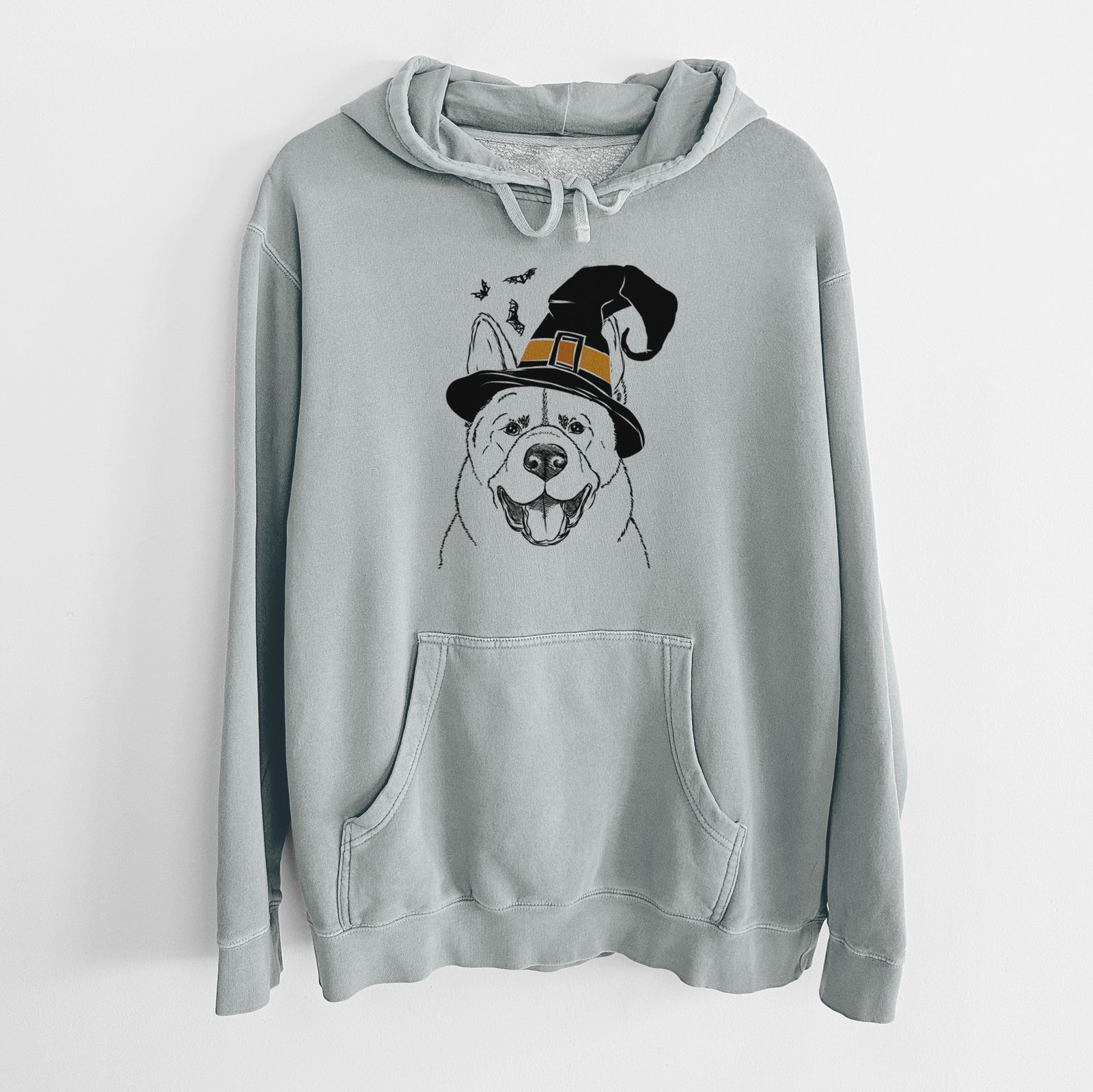 Hand-drawn sketch of Baku the Akita wearing a witch hat on a Sage Unisex pigment dyed hoodie