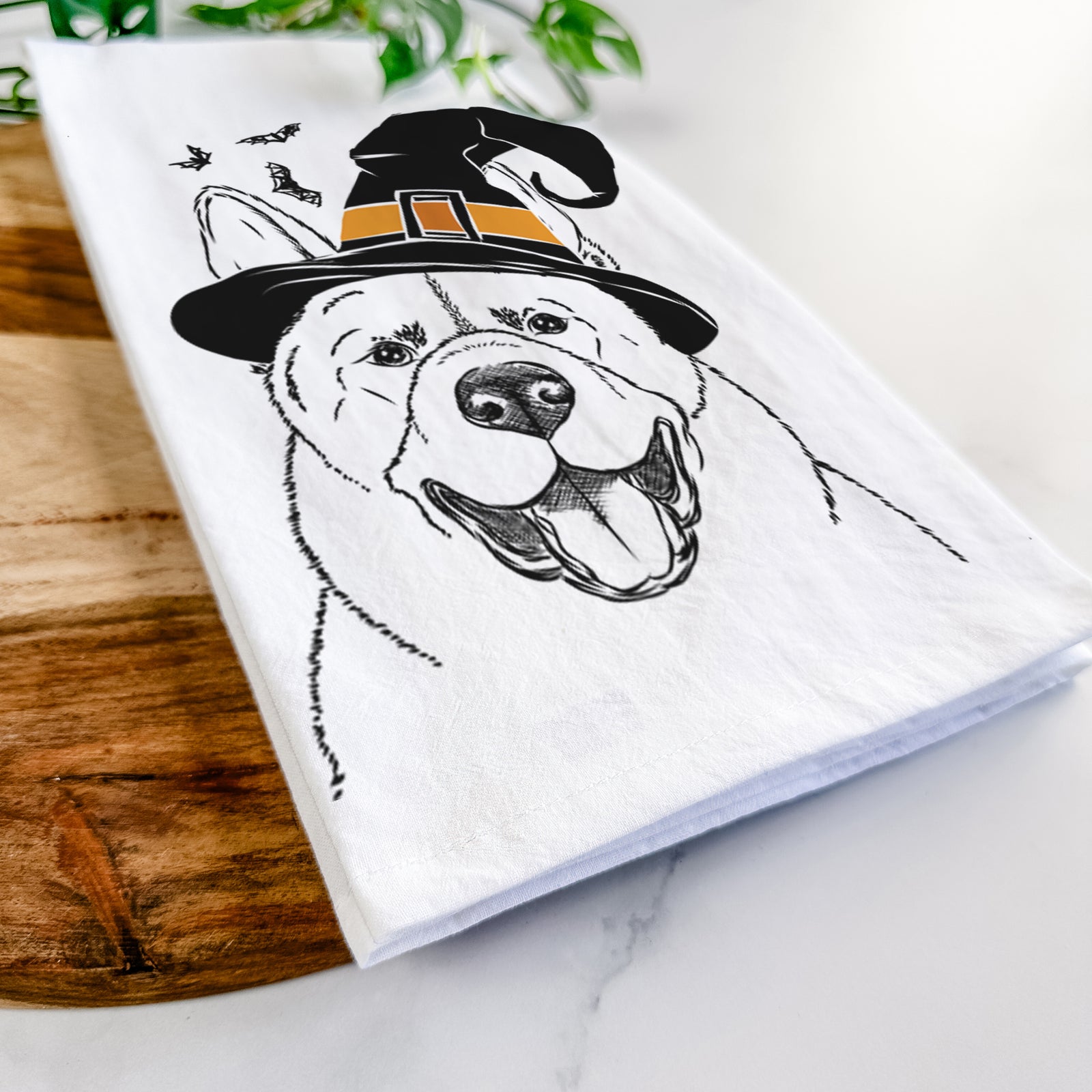 Hand-drawn sketch of Baku the Akita wearing a witch hat on a tea towel