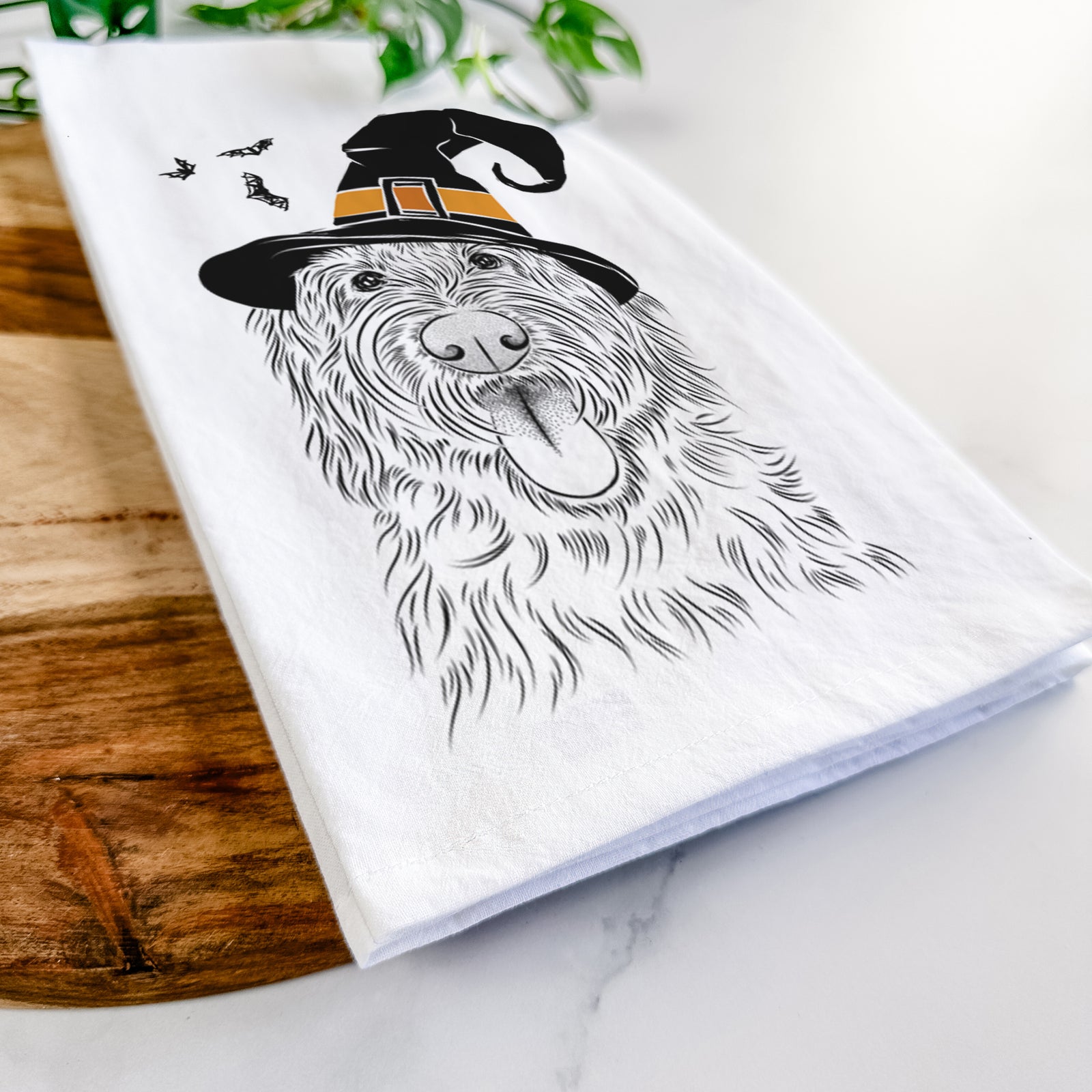 Hand-drawn sketch of Bennett the Doodle wearing a witch hat on a tea towel