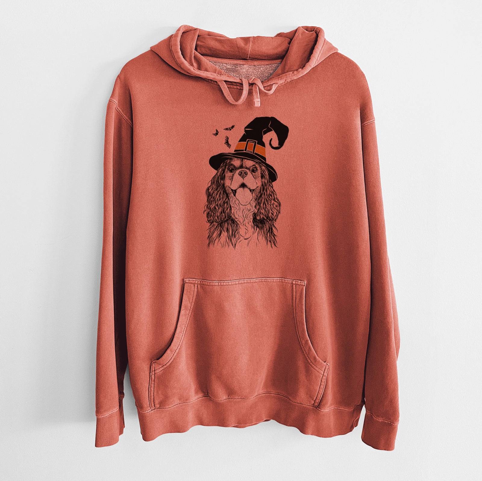 Hand-drawn sketch of Brandy the Cavalier King Charles Spaniel wearing a witch hat on an Amber Unisex pigment dyed hoodie
