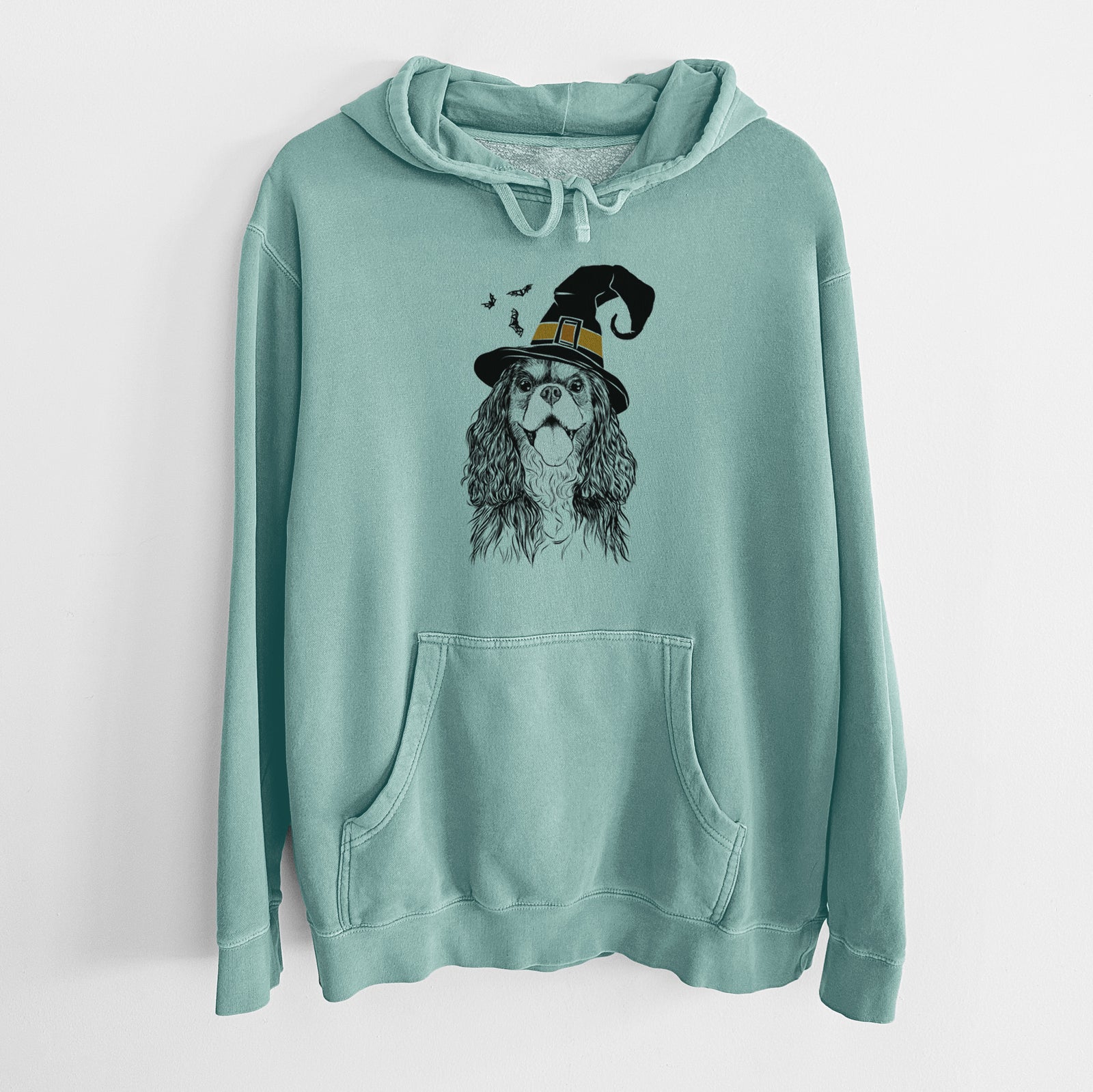 Hand-drawn sketch of Brandy the Cavalier King Charles Spaniel wearing a witch hat on a Mint Unisex pigment dyed hoodie