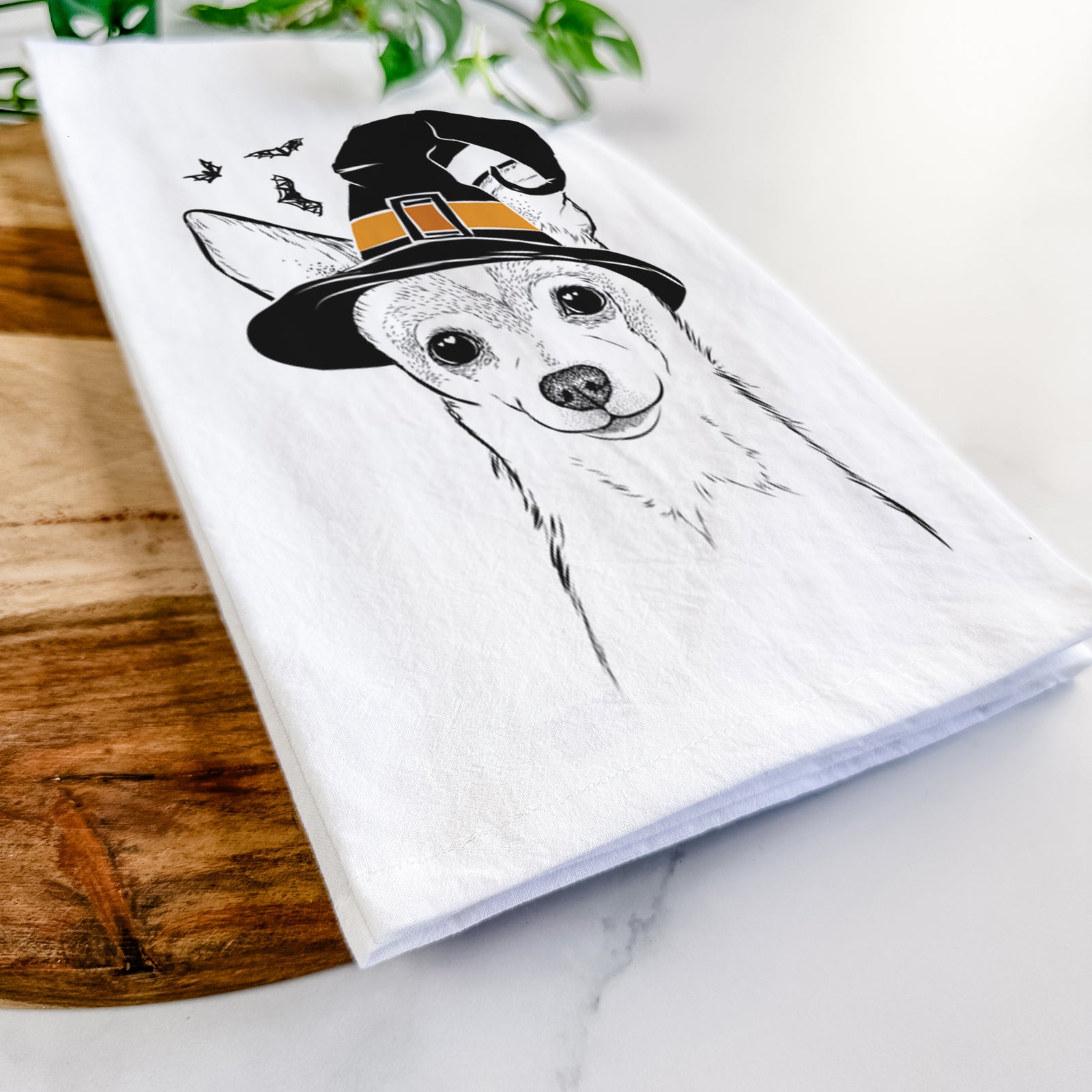 Hand-drawn sketch of Buggy the Chihuahua wearing a witch hat on a tea towel