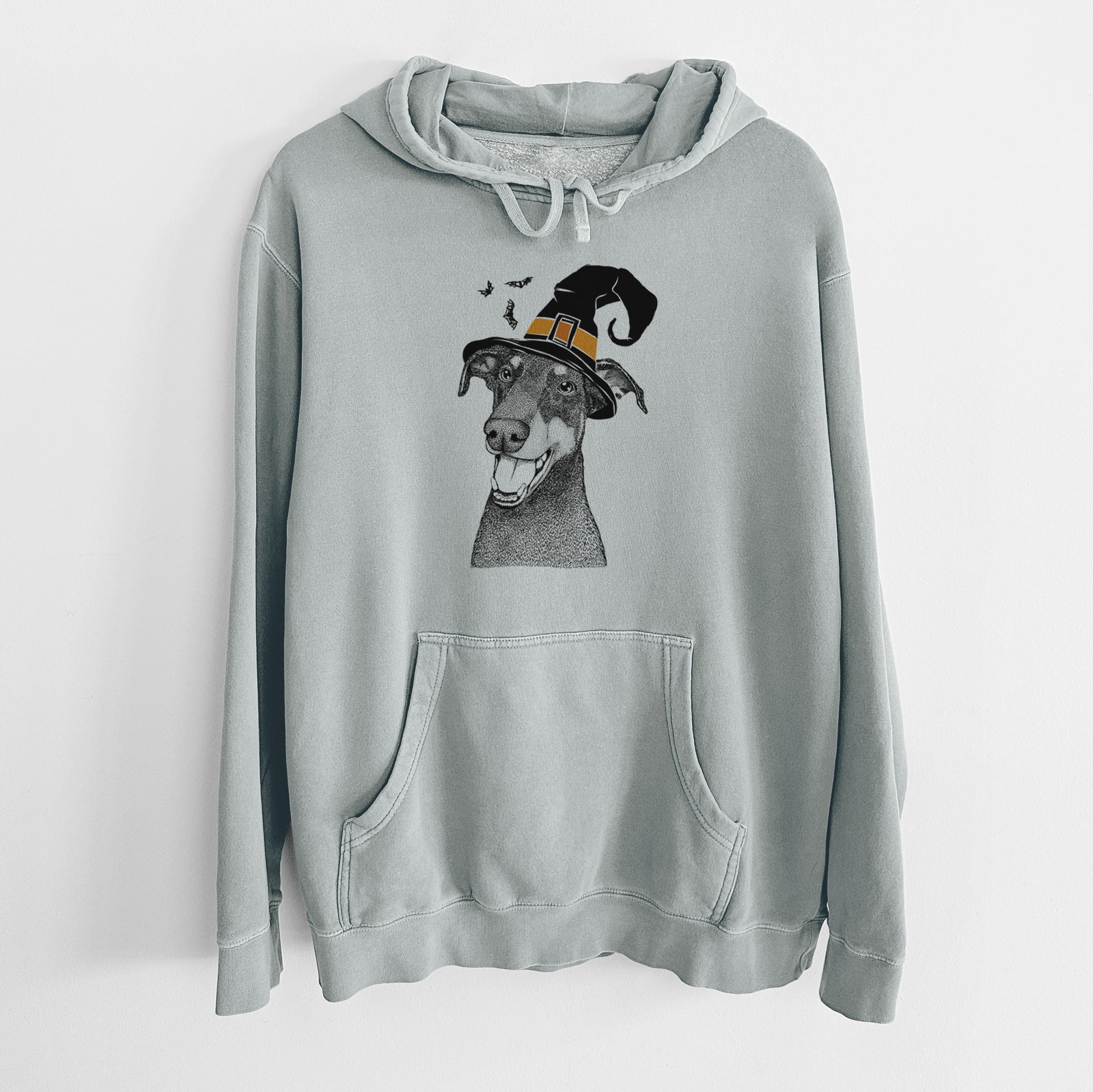 Hand-drawn sketch of Bunnie the Doberman Pinscher wearing a witch hat on a Sage Unisex pigment dyed hoodie