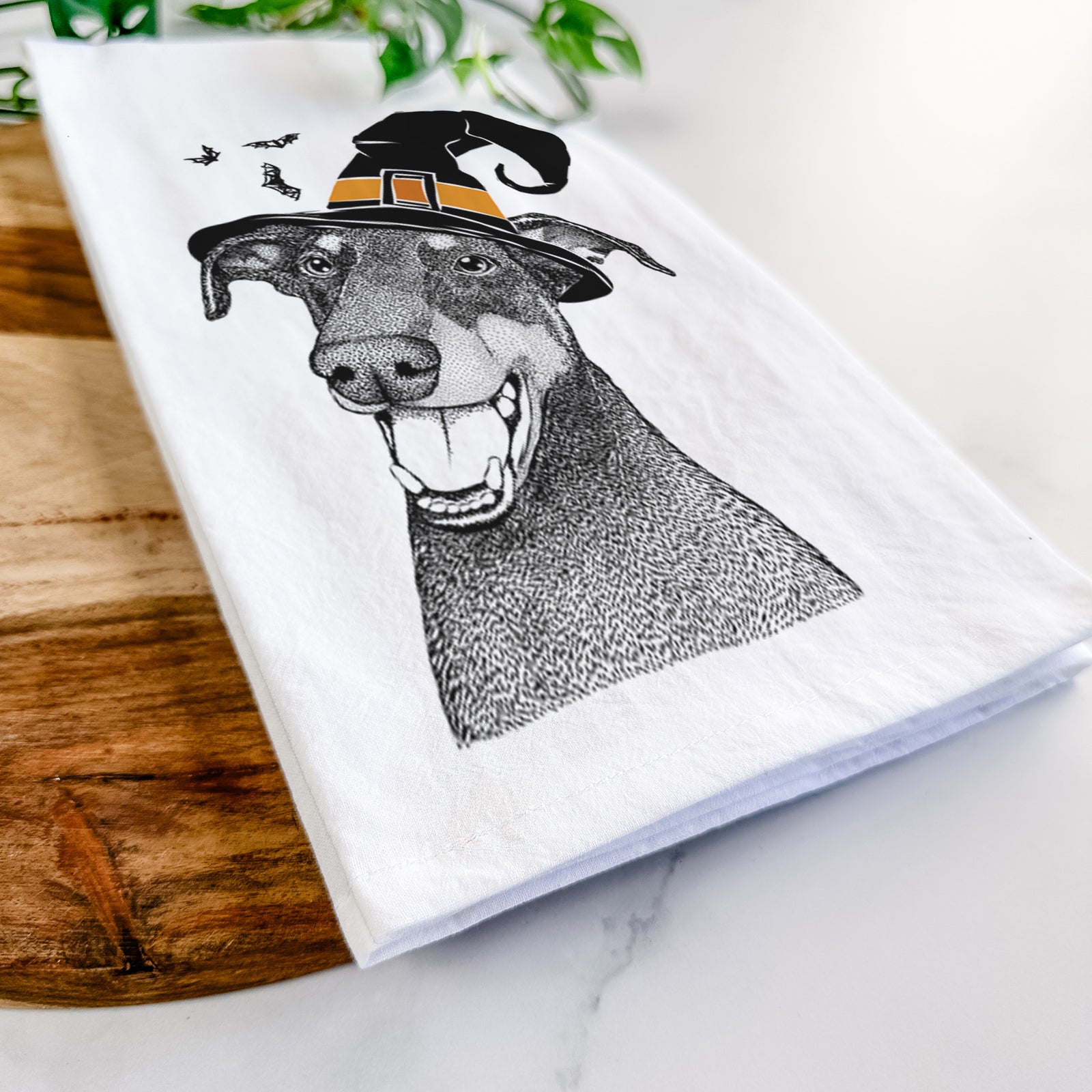 Hand-drawn sketch of Bunnie the Doberman Pinscher wearing a witch hat on a tea towel