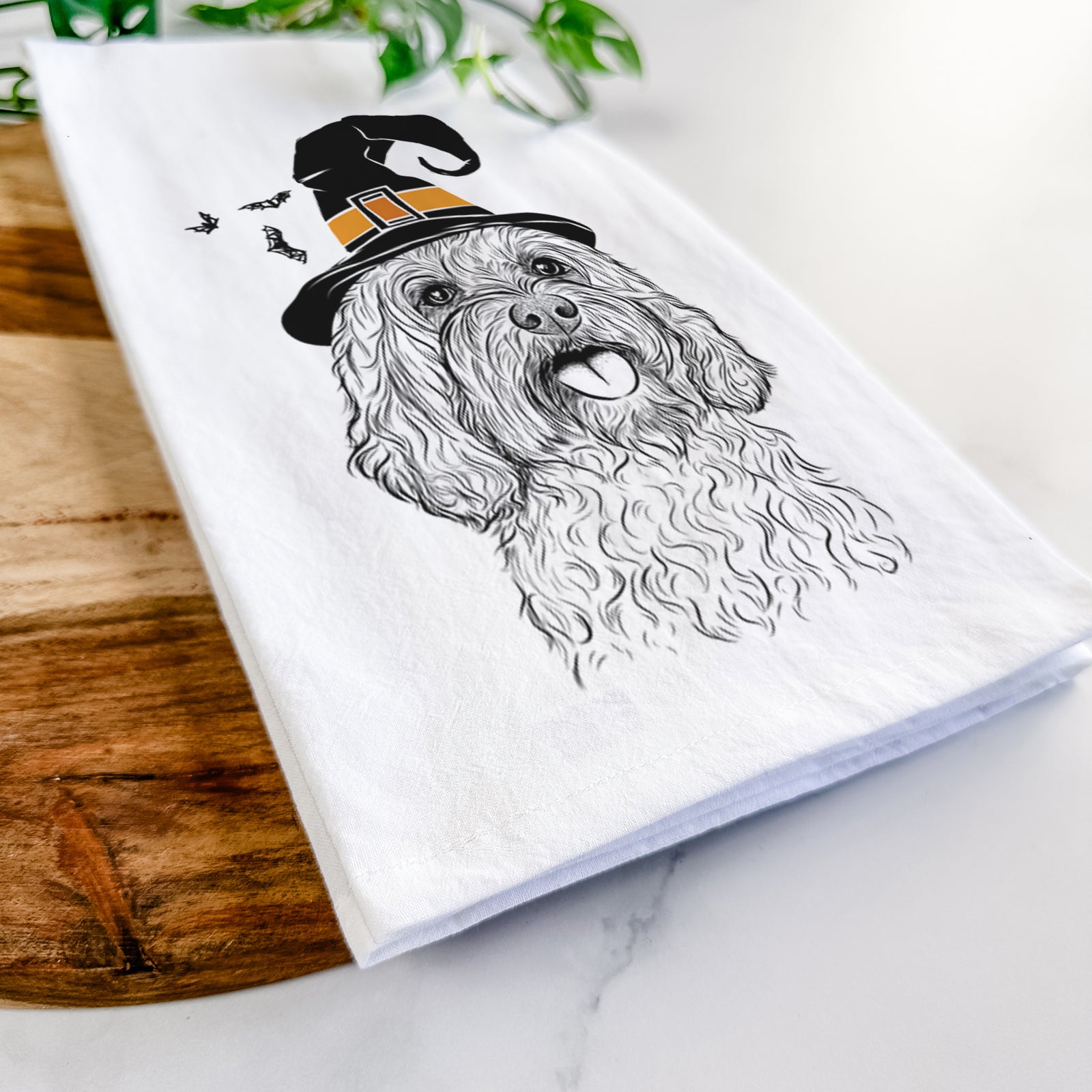 Hand-drawn sketch of Cali the Cavapoo wearing a witch hat on a tea towel