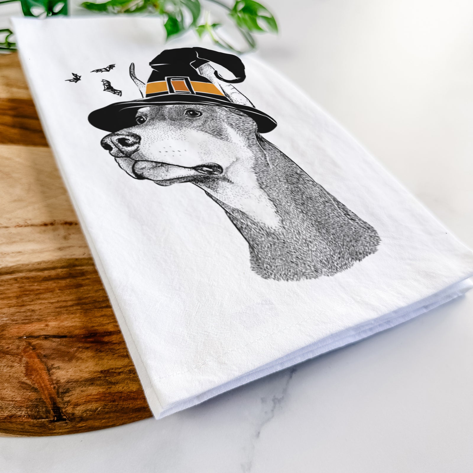 Hand-drawn sketch of Cenza the Doberman Pinscher wearing a witch hat on a tea towel