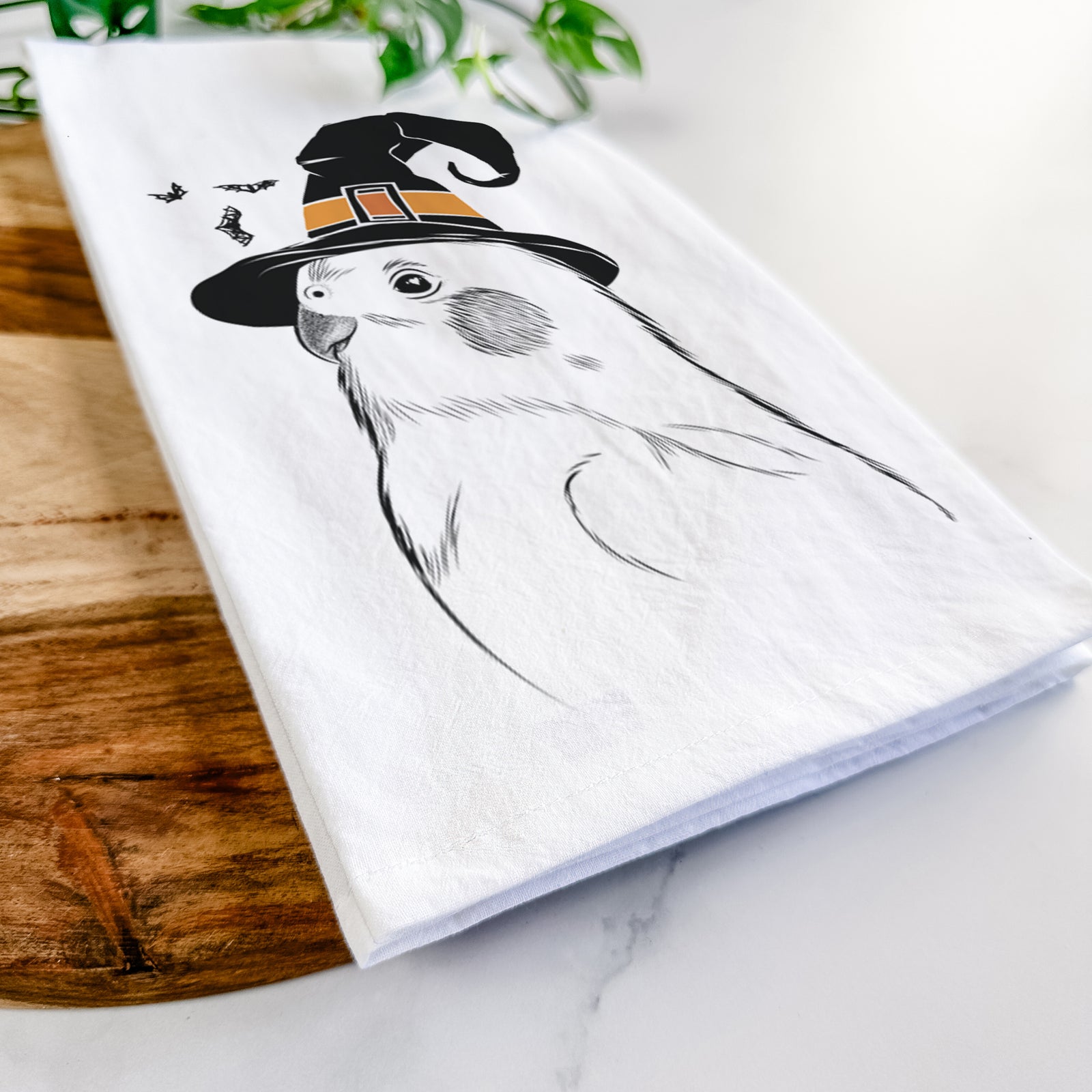 Hand-drawn sketch of Charlie the Cockatiel wearing a witch hat on a tea towel