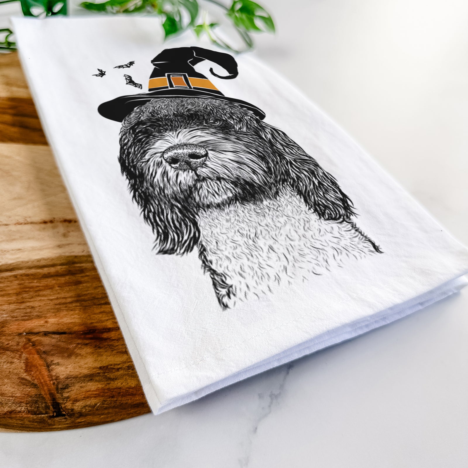 Hand-drawn sketch of Chris the Portuguese Water Dog wearing a witch hat on a tea towel