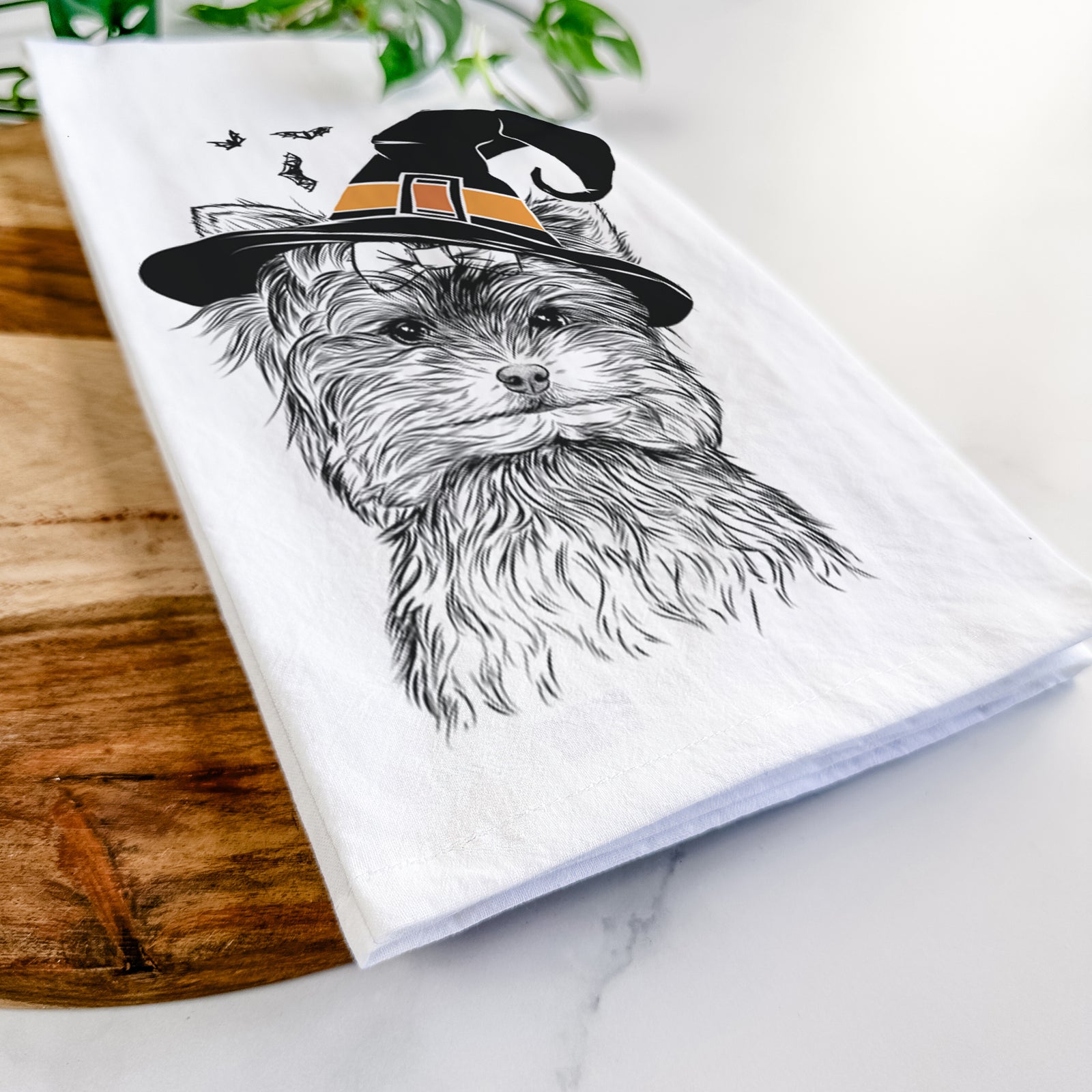 Hand-drawn sketch of Cricket the Biewer Terrier wearing a witch hat on a tea towel
