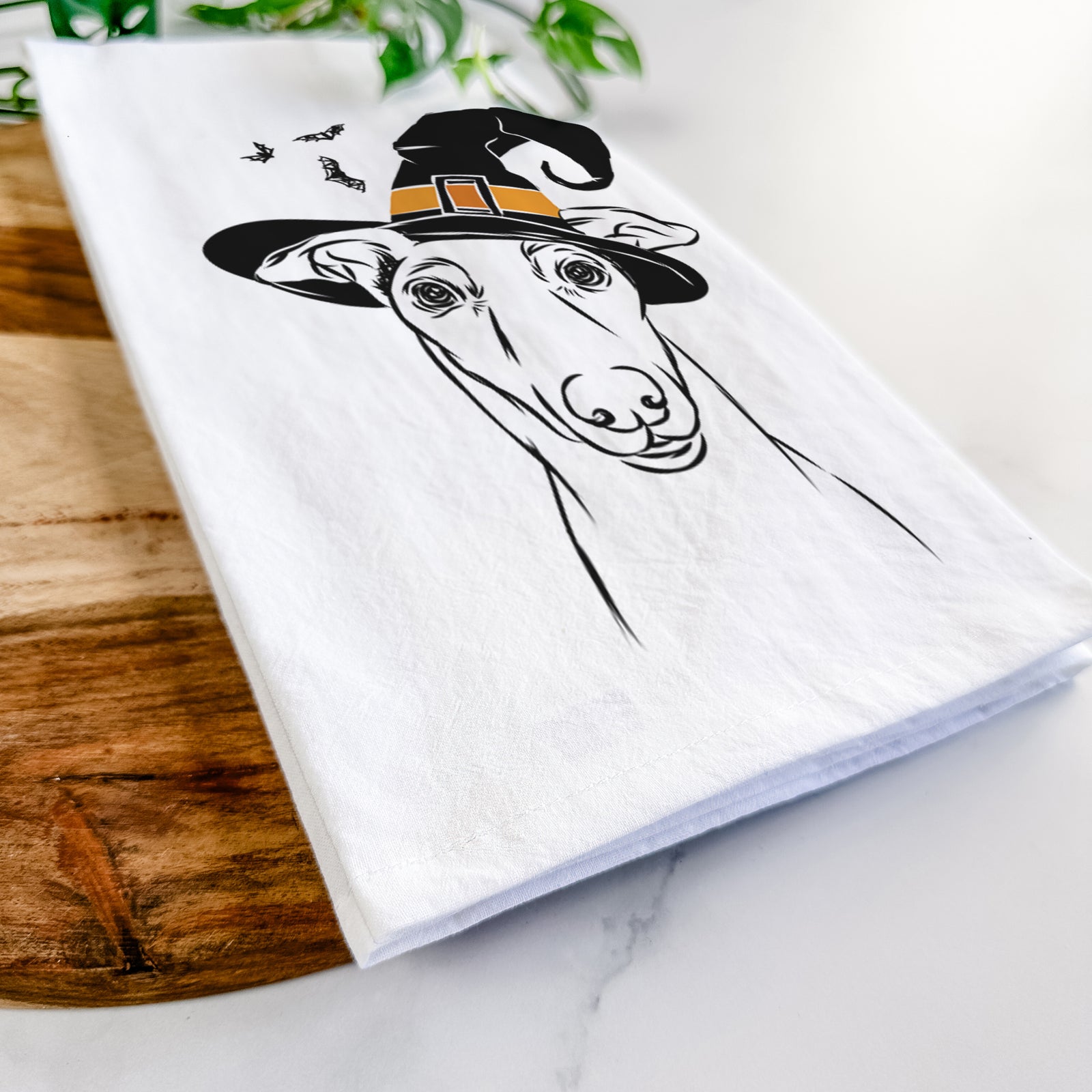 Hand-drawn sketch of Diva the Greyhound wearing a witch hat on a tea towel