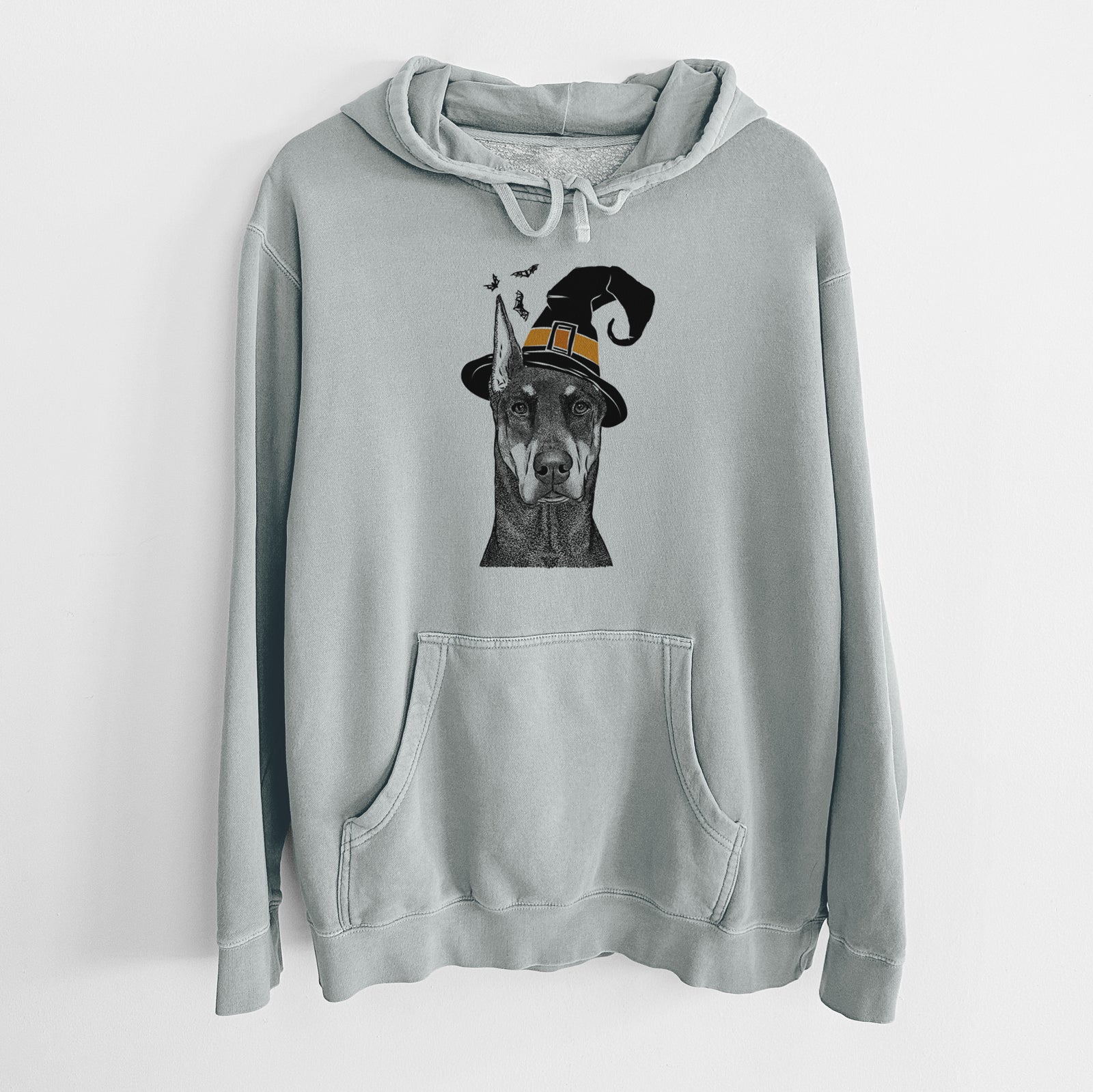 Hand-drawn sketch of Drake the Doberman Pinscher wearing a witch hat on a Sage Unisex pigment dyed hoodie
