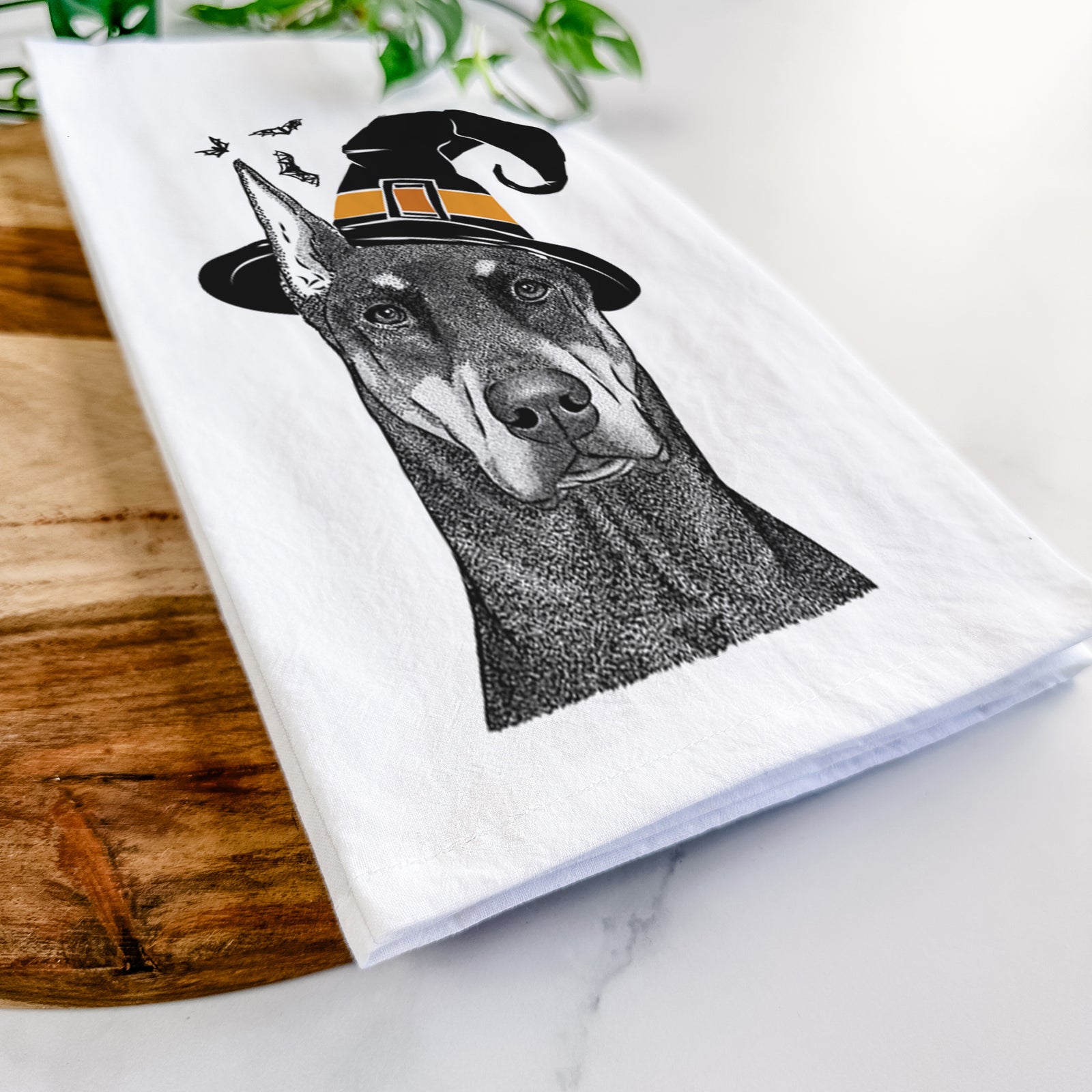Hand-drawn sketch of Drake the Doberman Pinscher wearing a witch hat on a tea towel