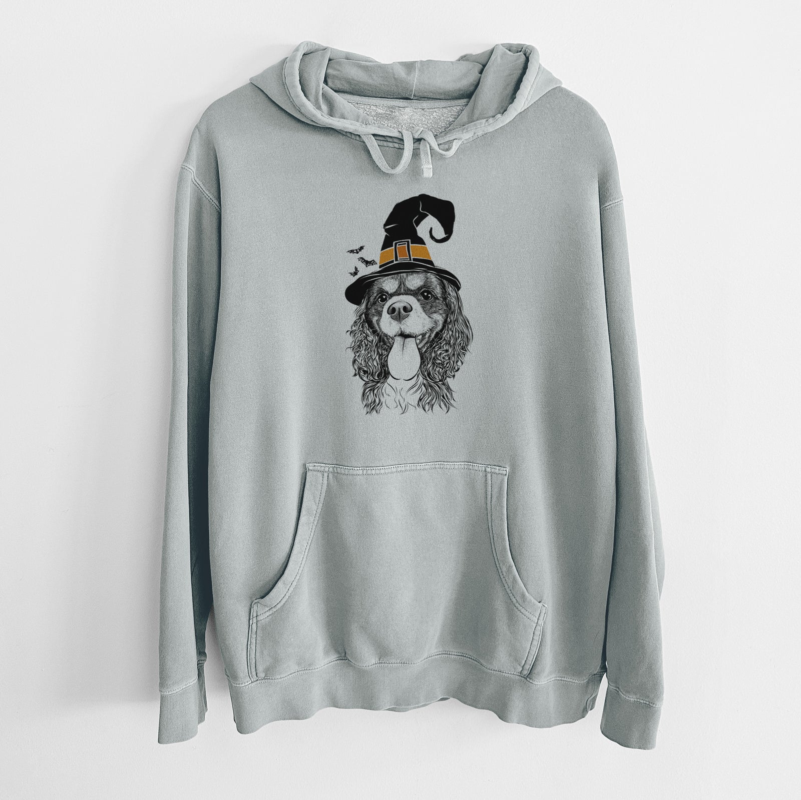 Hand-drawn sketch of Elizabeth the Cavalier King Charles Spaniel wearing a witch hat on a Sage Unisex pigment dyed hoodie