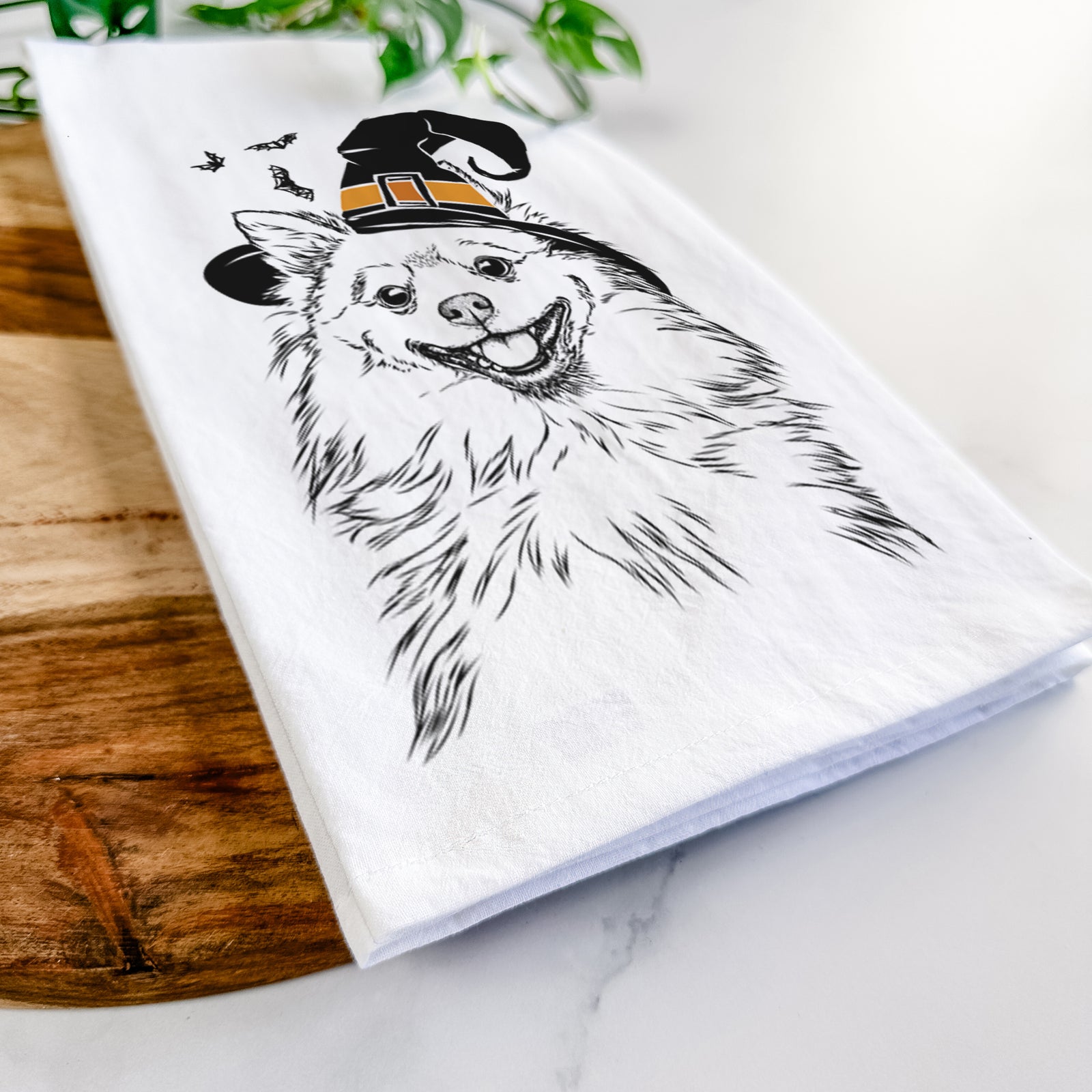 Hand-drawn sketch of Fibi the Spitz wearing a witch hat on a tea towel