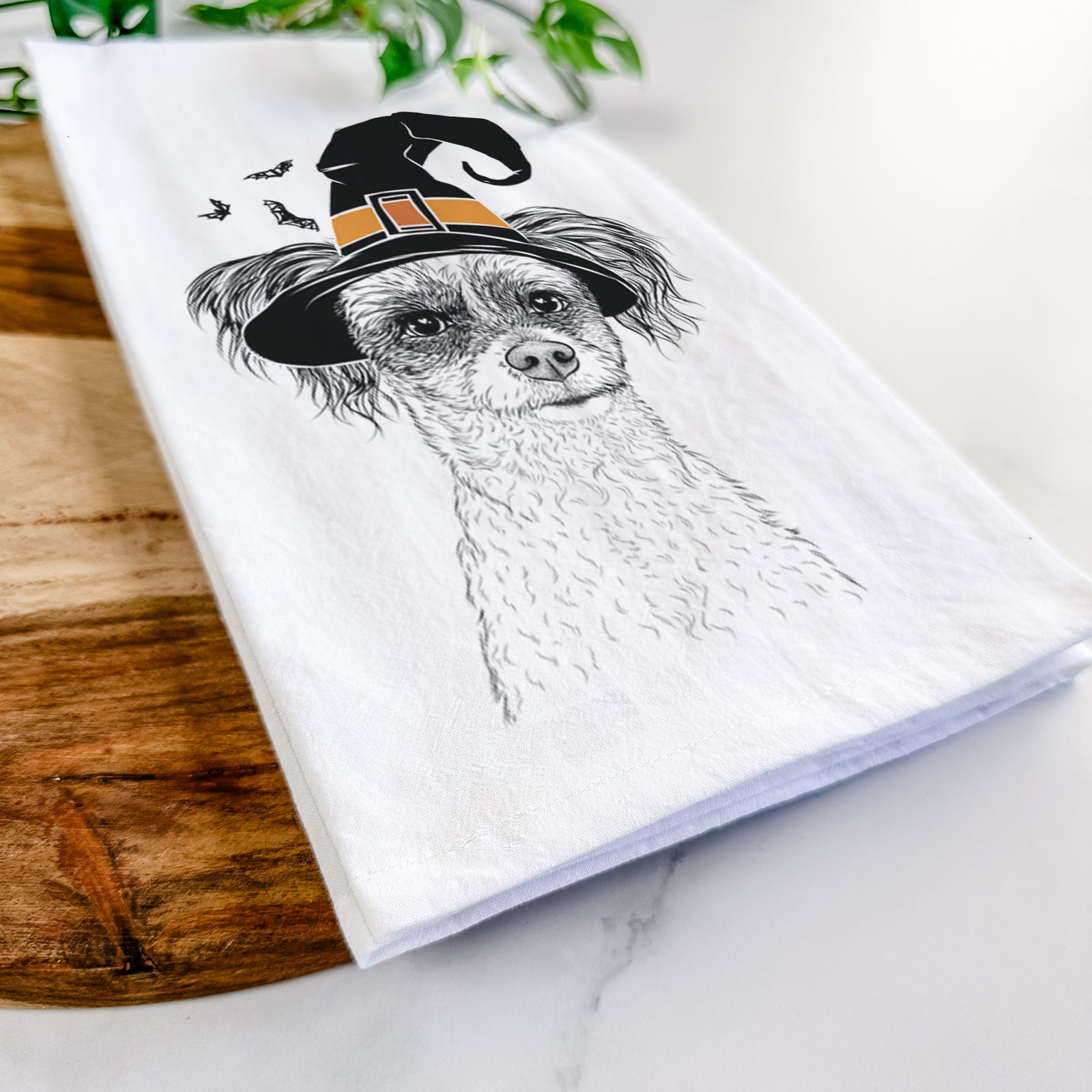 Hand-drawn sketch of Finley the Papillon Mix wearing a witch hat on a tea towel