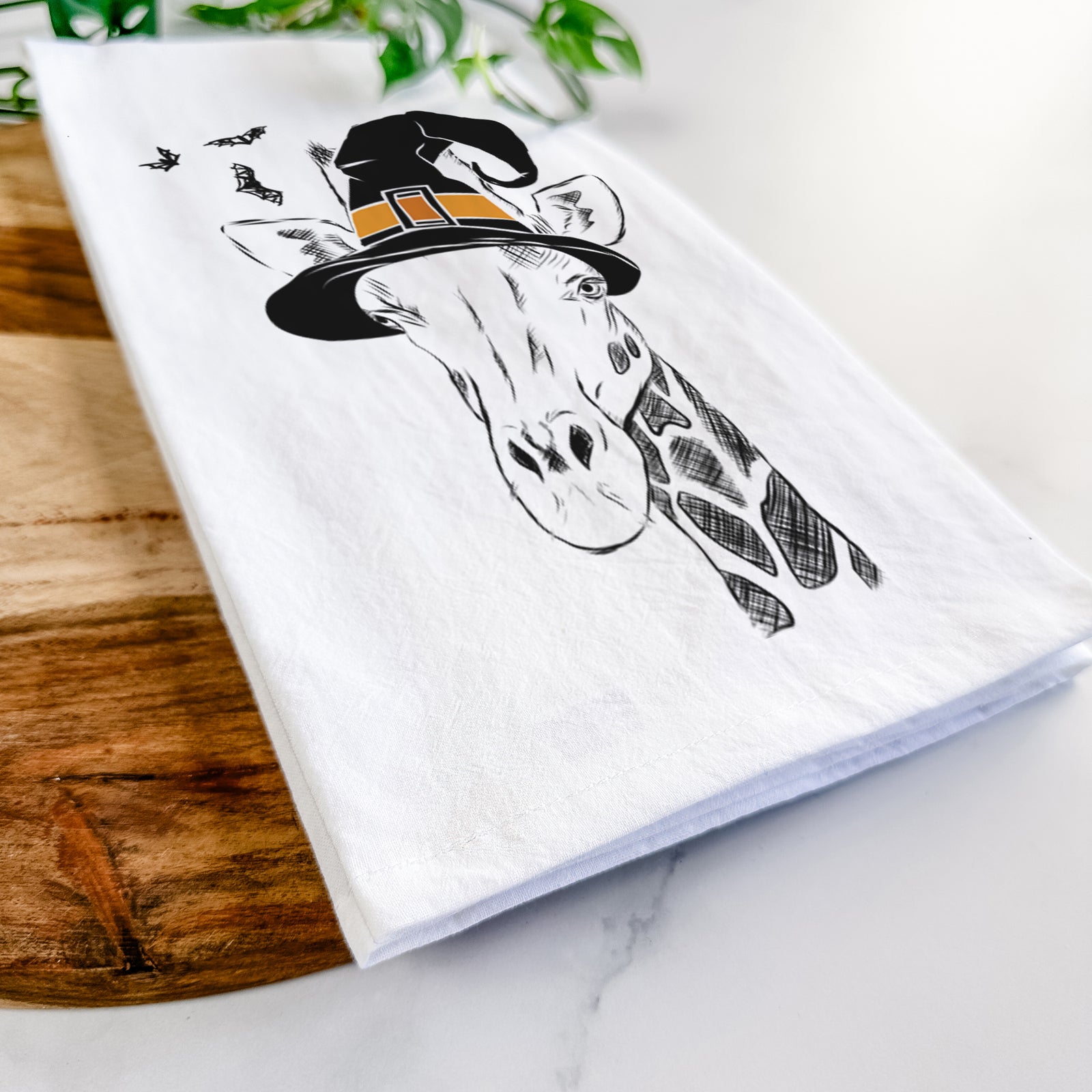 Hand-drawn sketch of Geoffrey the Giraffe wearing a witch hat on a tea towel