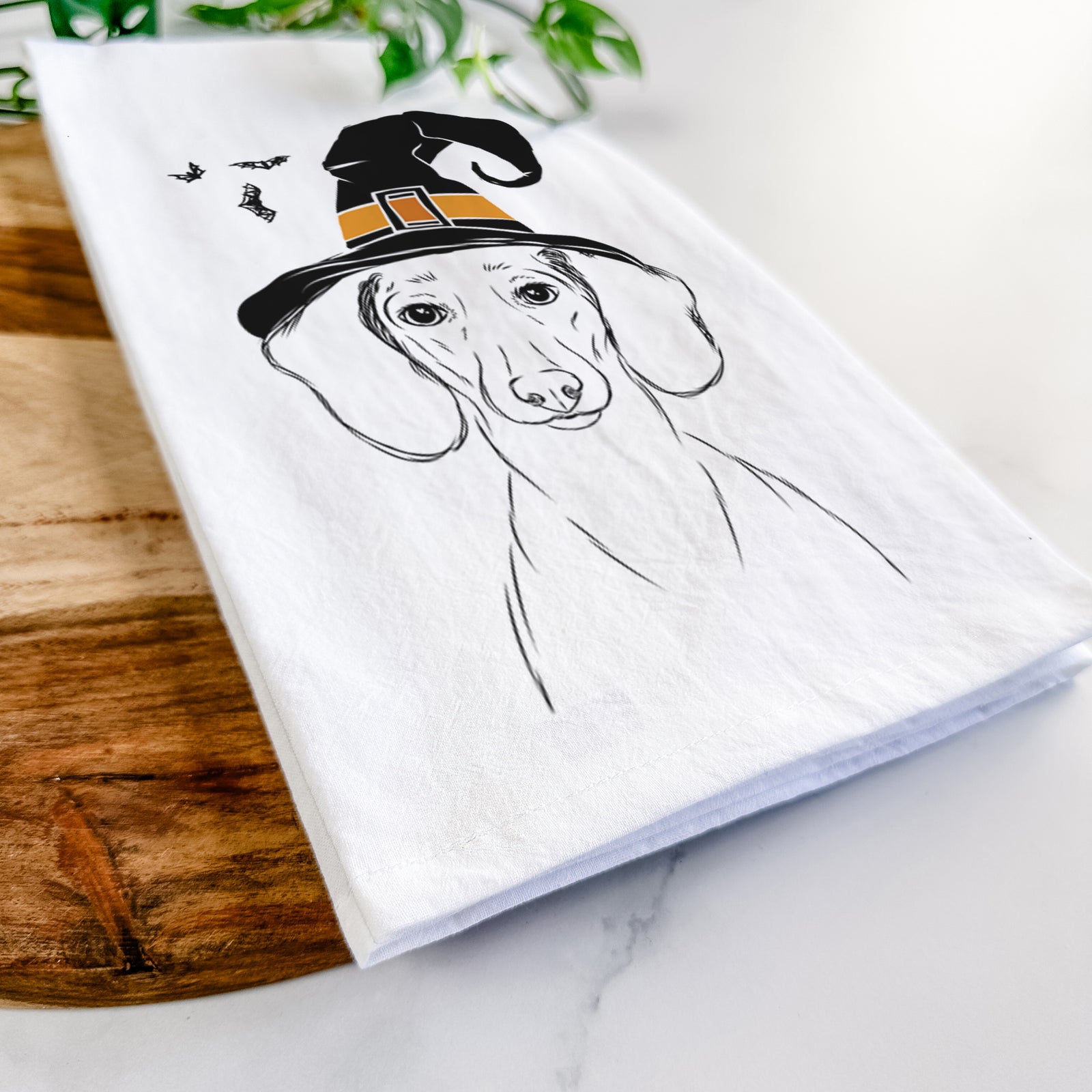 Hand-drawn sketch of Hans the Dachshund wearing a witch hat on a tea towel