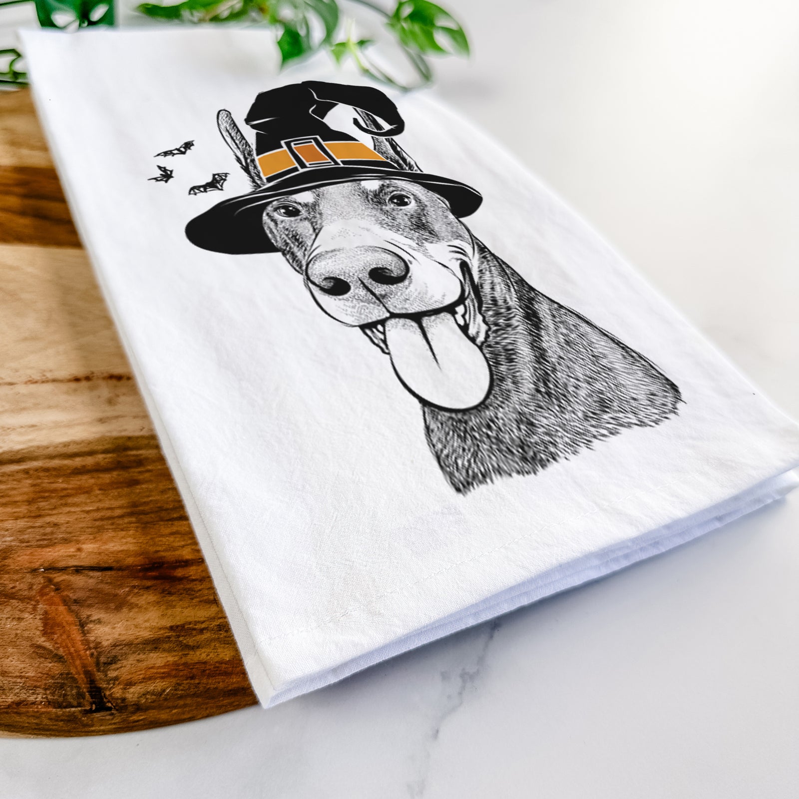 Hand-drawn sketch of Happy Sunny the Doberman Pinscher wearing a witch hat on a tea towel