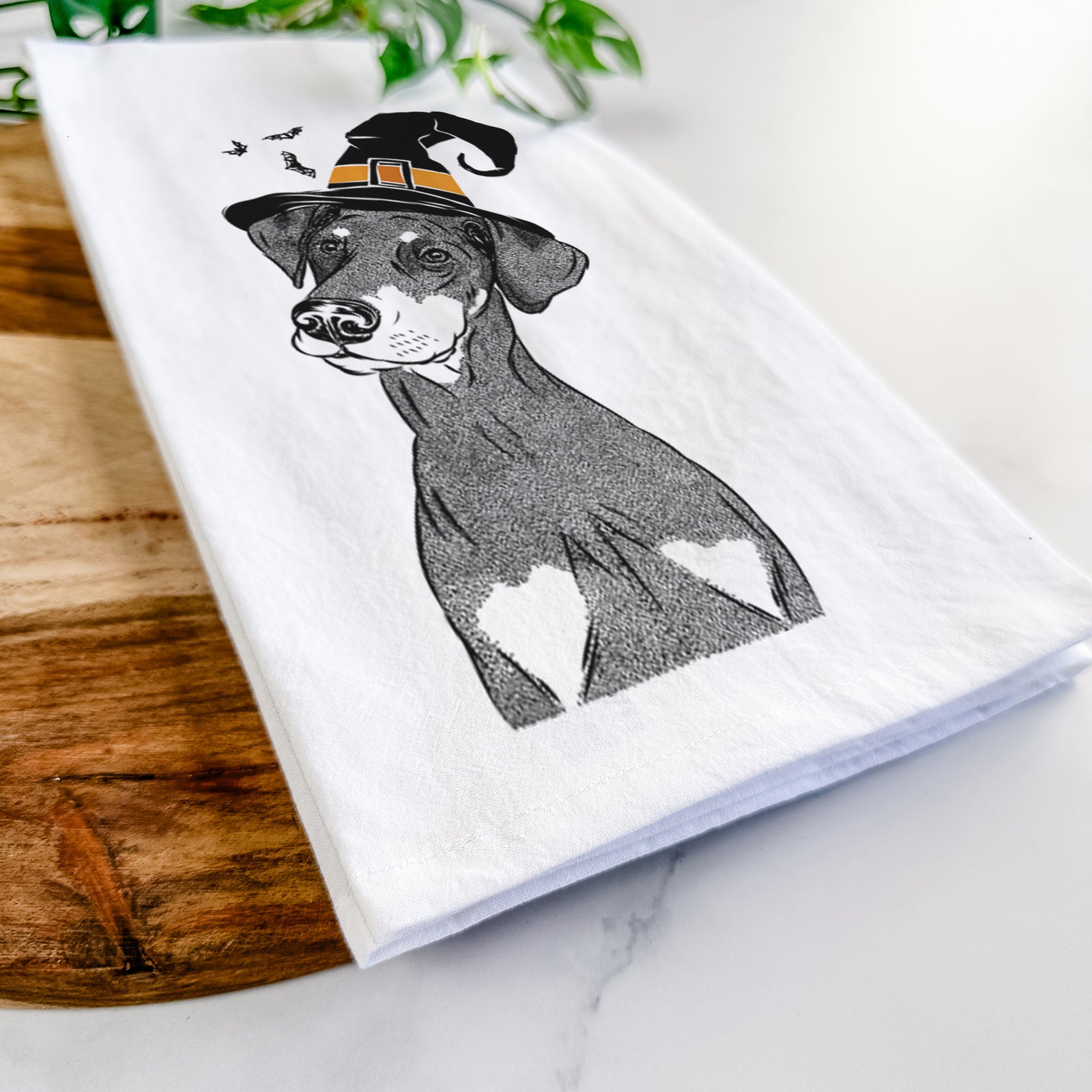 Hand-drawn sketch of Iroh the Doberman Pinscher wearing a witch hat on a tea towel