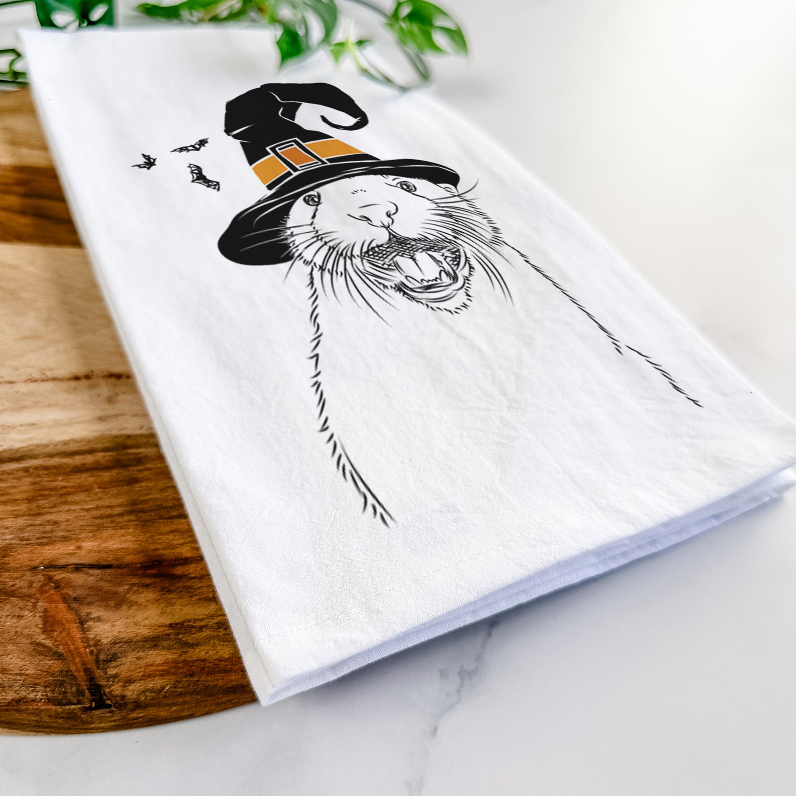 Hand-drawn sketch of Jasper the River Otter wearing a witch hat on a tea towel