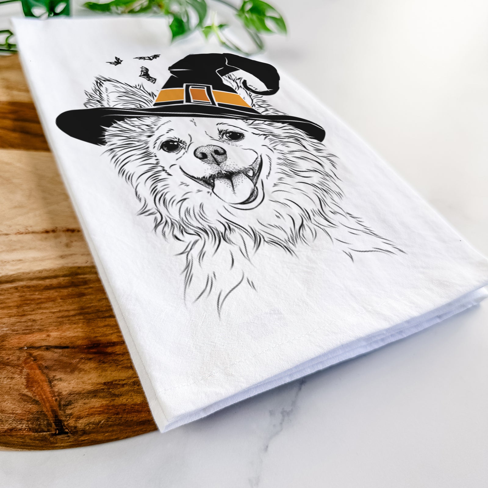 Hand-drawn sketch of Jasper the Pomchi wearing a witch hat on a tea towel