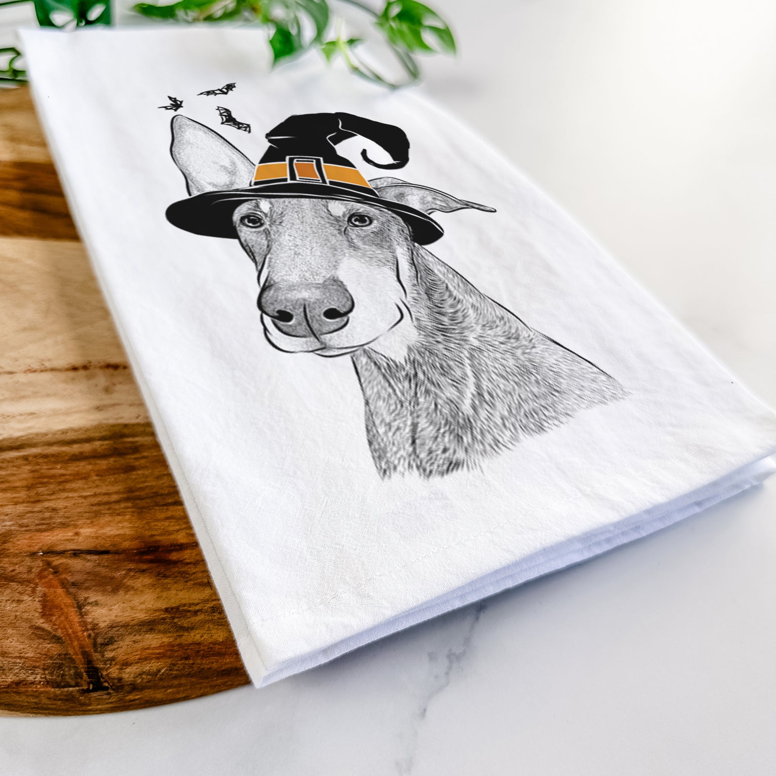 Hand-drawn sketch of Kain the Doberman Pinscher wearing a witch hat on a tea towel