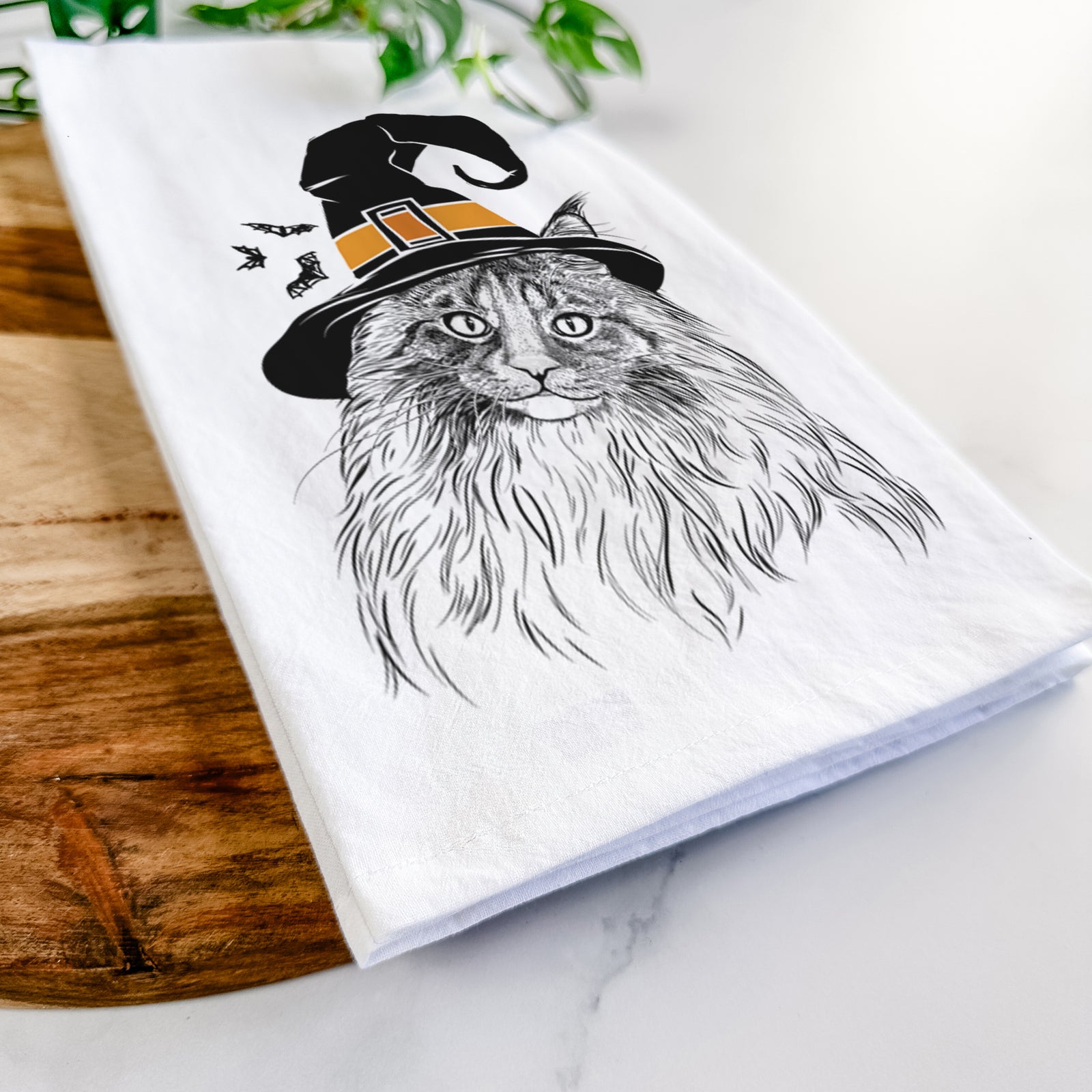 Hand-drawn sketch of Kiki the Maine Coon Cat wearing a witch hat on a tea towel