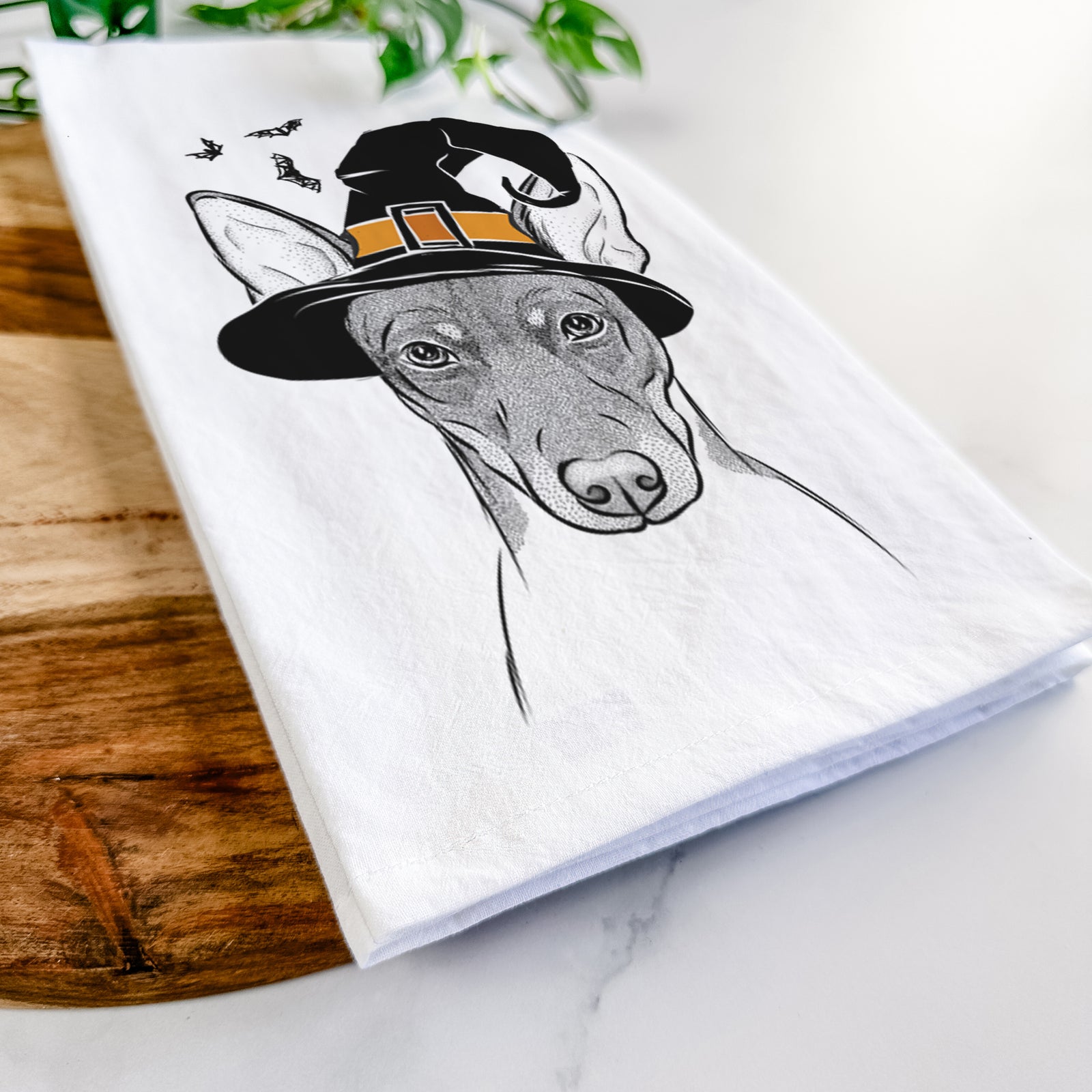 Hand-drawn sketch of Knox the Rat Terrier wearing a witch hat on a tea towel