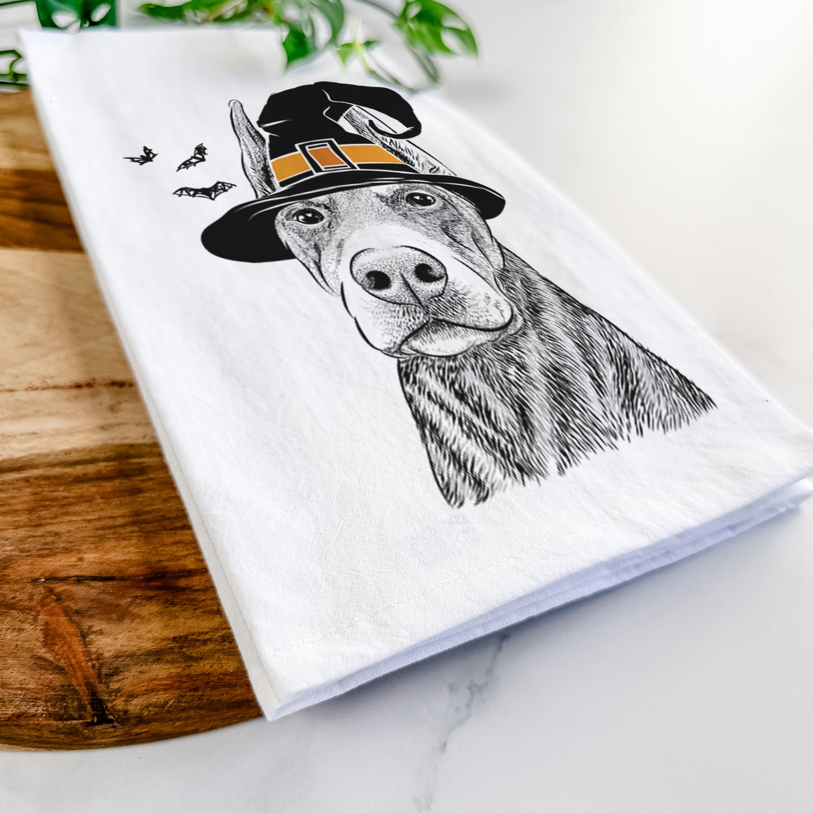 Hand-drawn sketch of Luna the Doberman Pinscher wearing a witch hat on a tea towel