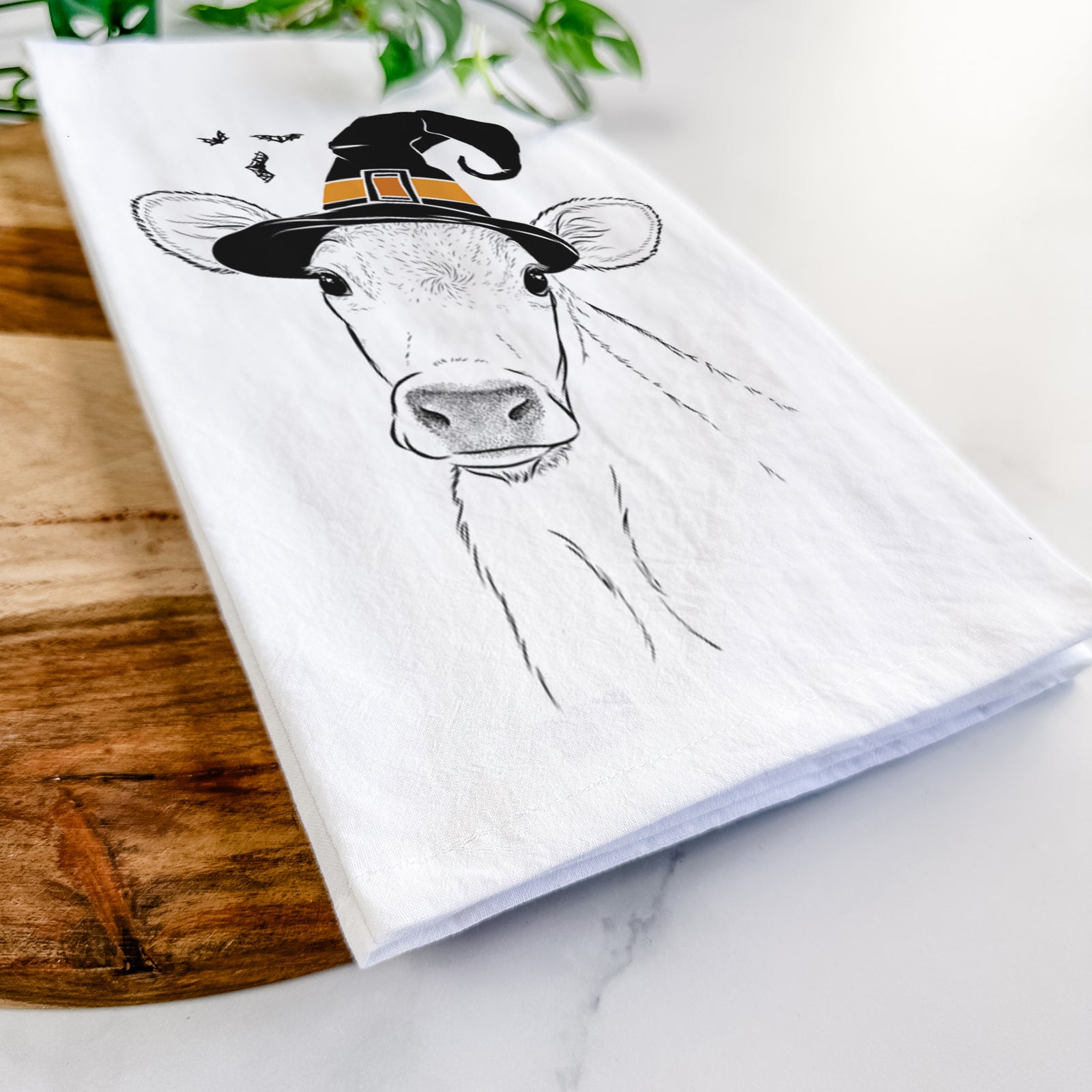 Hand-drawn sketch of Malu the Cow wearing a witch hat on a tea towel