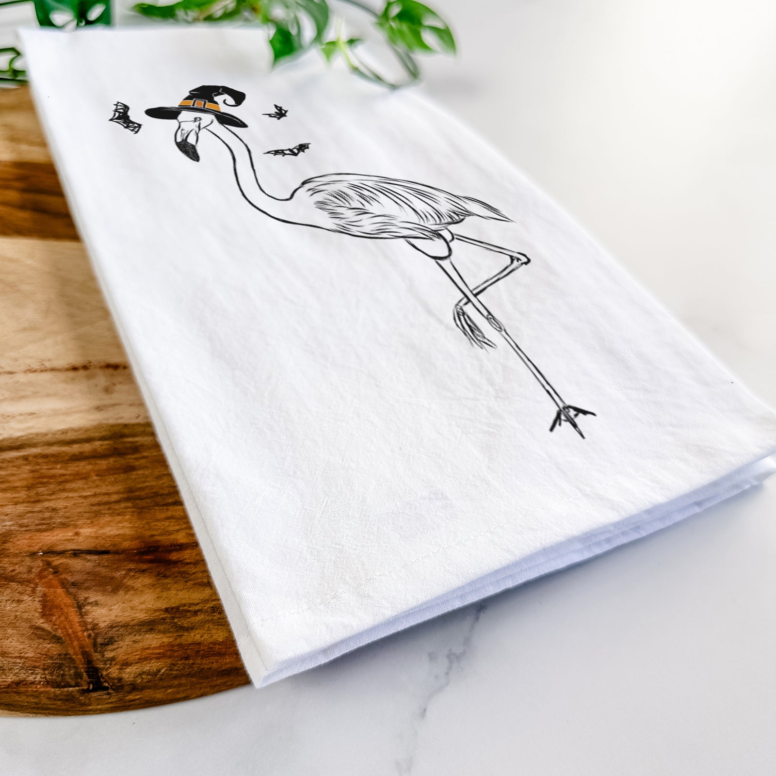 Hand-drawn sketch of Mango the Flamingo wearing a witch hat on a tea towel