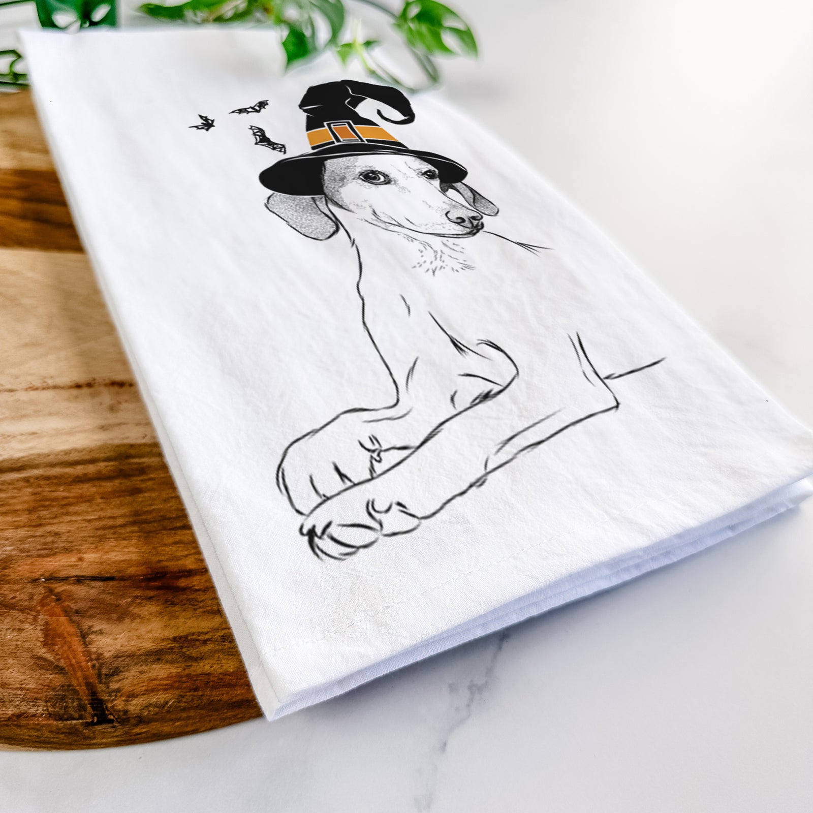 Hand-drawn sketch of Opie the Foxhound wearing a witch hat on a tea towel