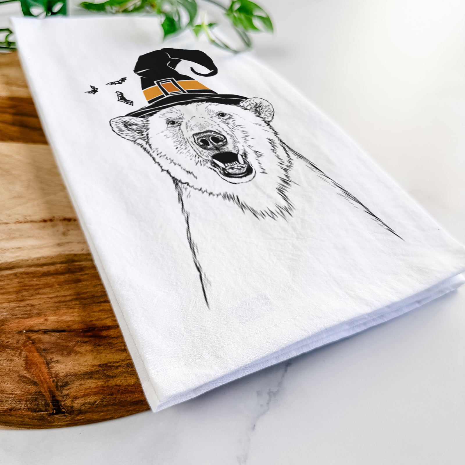 Hand-drawn sketch of Oslo the Polar Bear wearing a witch hat on a tea towel