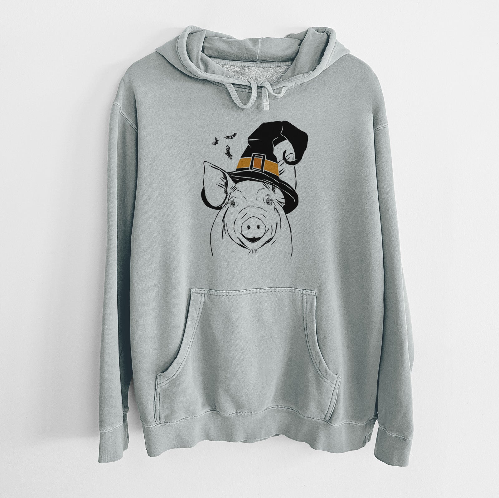 Hand-drawn sketch of Perry the Pig wearing a witch hat on a Sage Unisex pigment dyed hoodie
