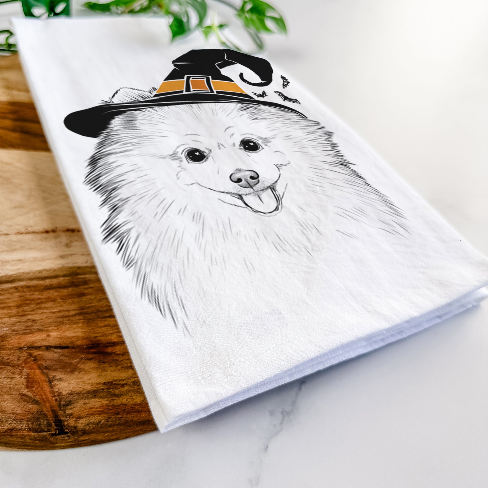 Hand-drawn sketch of Piper Jo the Pomeranian wearing a witch hat on a tea towel