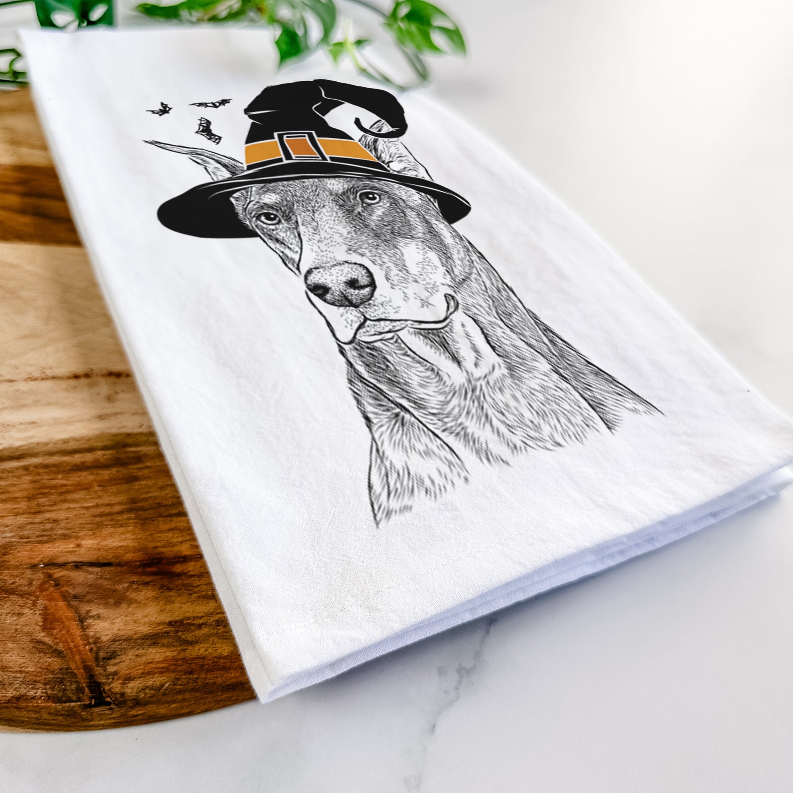 Hand-drawn sketch of RJ the Doberman Pinscher wearing a witch hat on a tea towel
