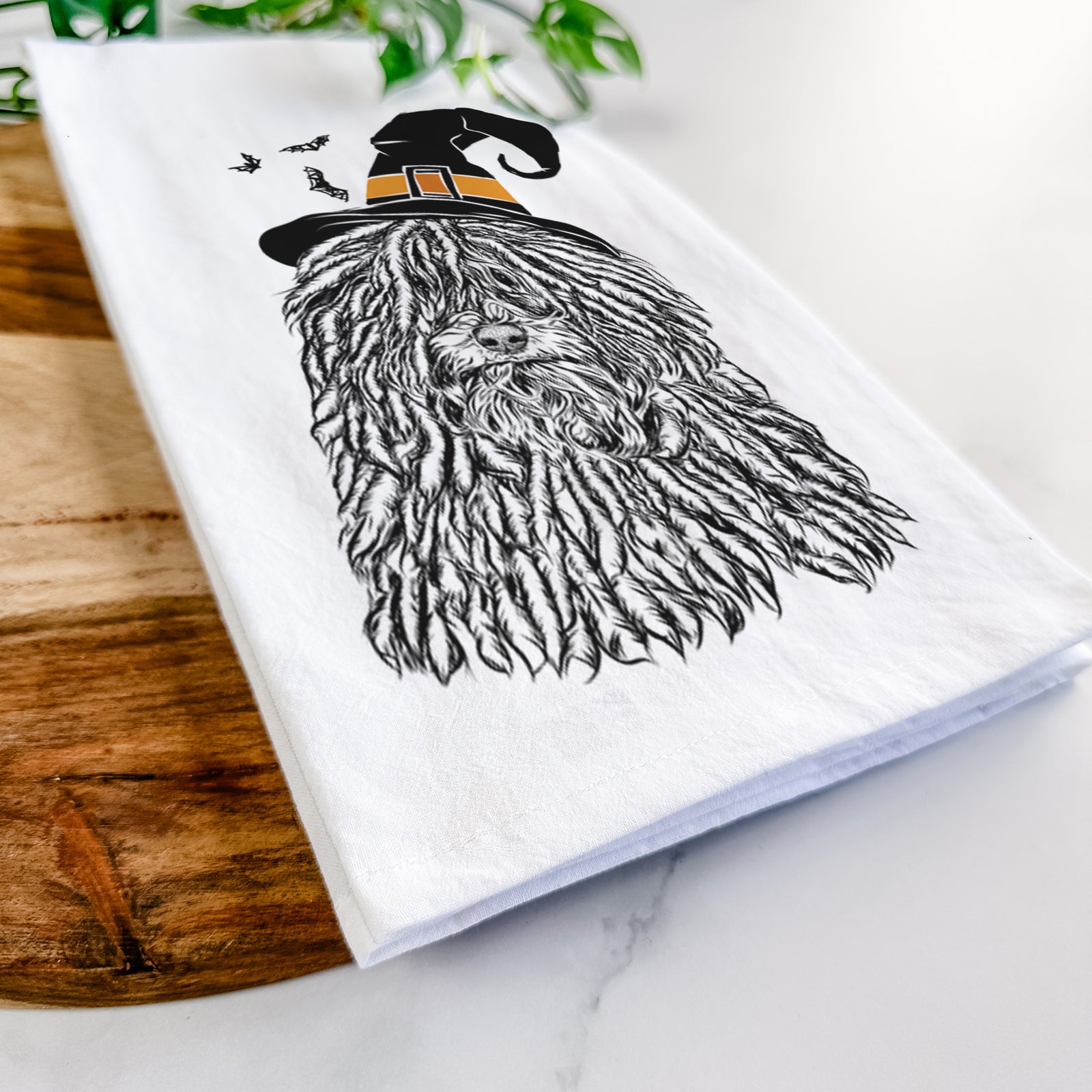 Hand-drawn sketch of Rezi the Puli wearing a witch hat on a tea towel