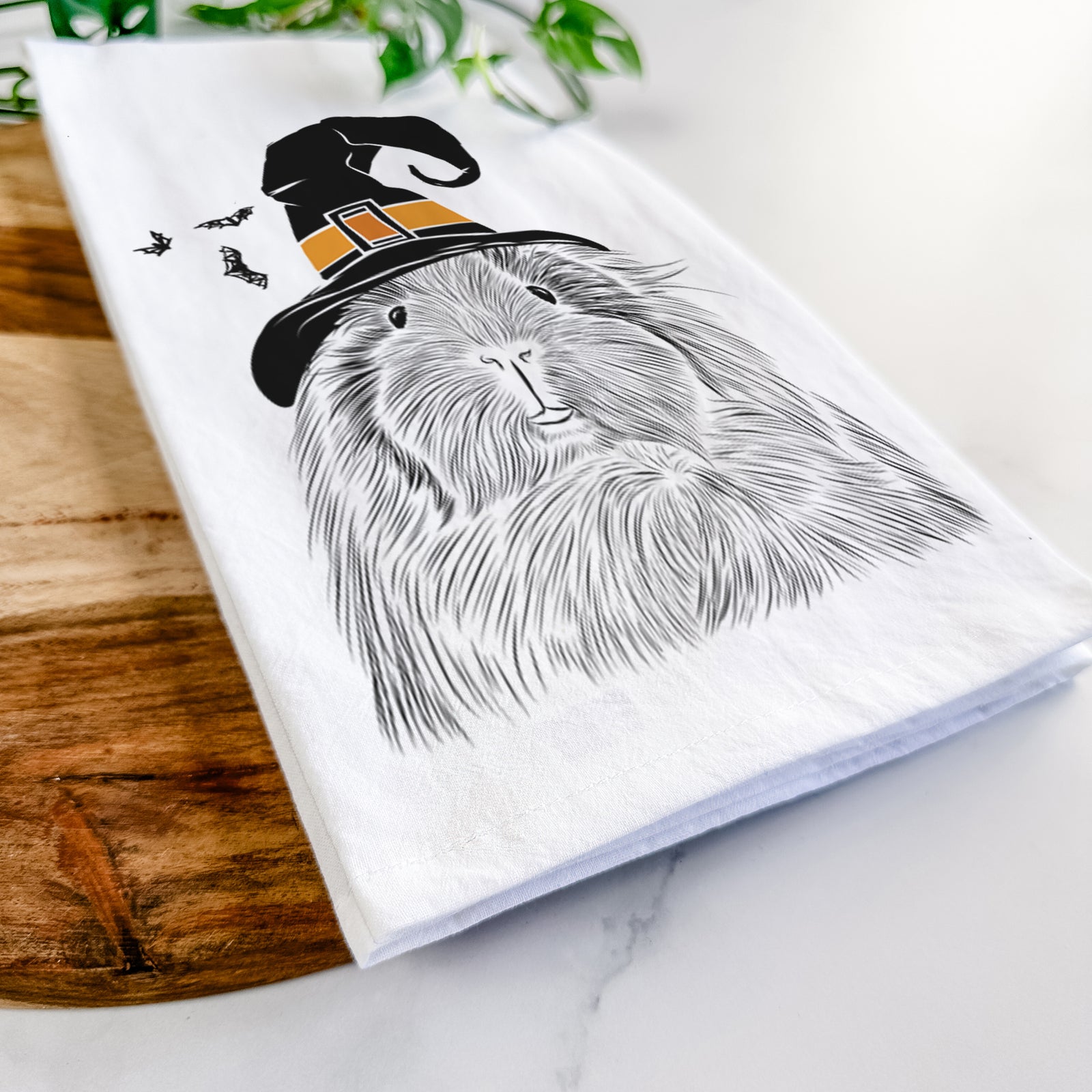 Hand-drawn sketch of Rhino the Guinea Pig wearing a witch hat on a tea towel