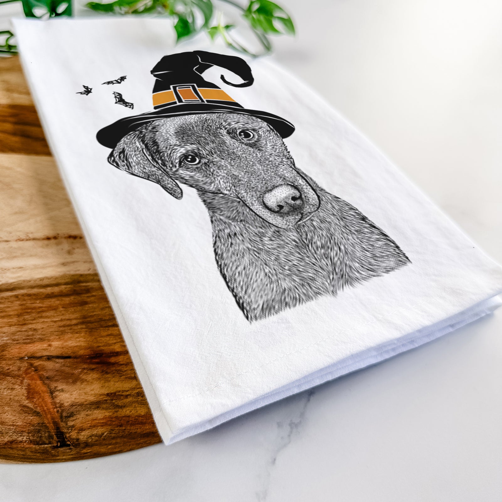 Hand-drawn sketch of Sadie the Whipador wearing a witch hat on a tea towel