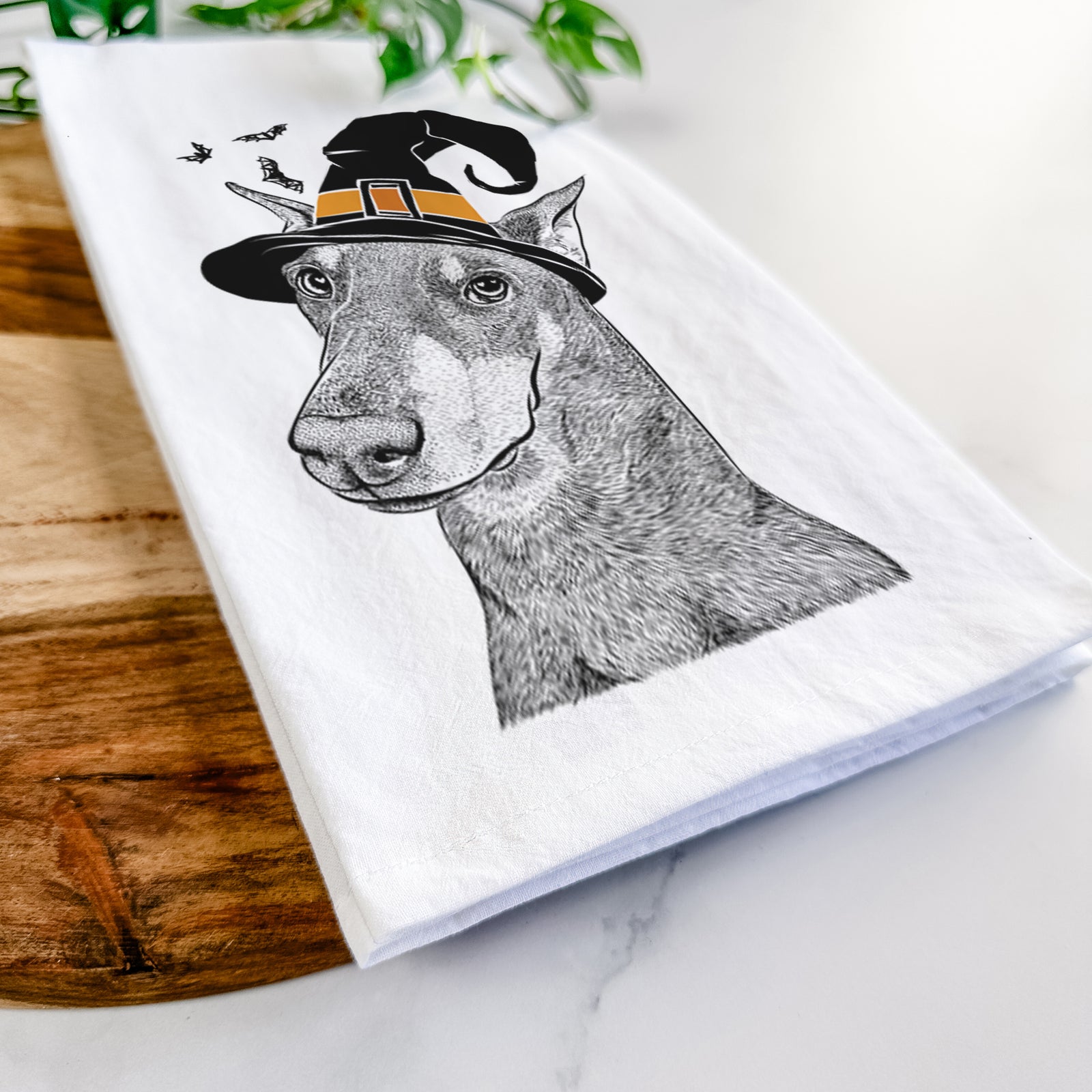 Hand-drawn sketch of Shelby the Doberman Pinscher wearing a witch hat on a tea towel