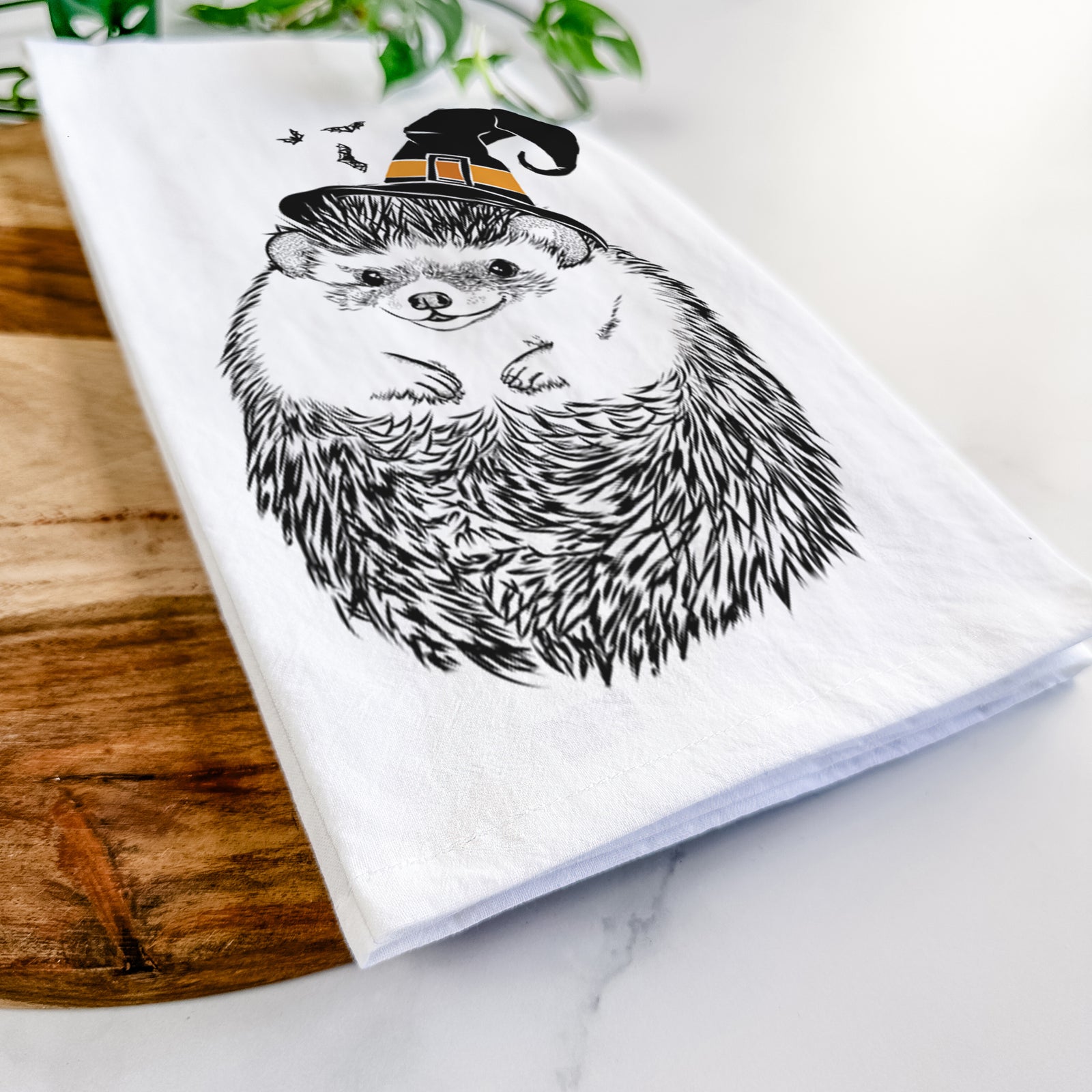 Hand-drawn sketch of Sid the Hedgehog wearing a witch hat on a tea towel