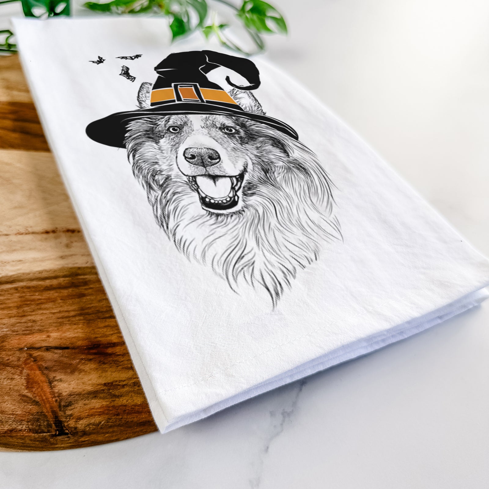 Hand-drawn sketch of Skylar the Shetland Sheepdog wearing a witch hat on a tea towel