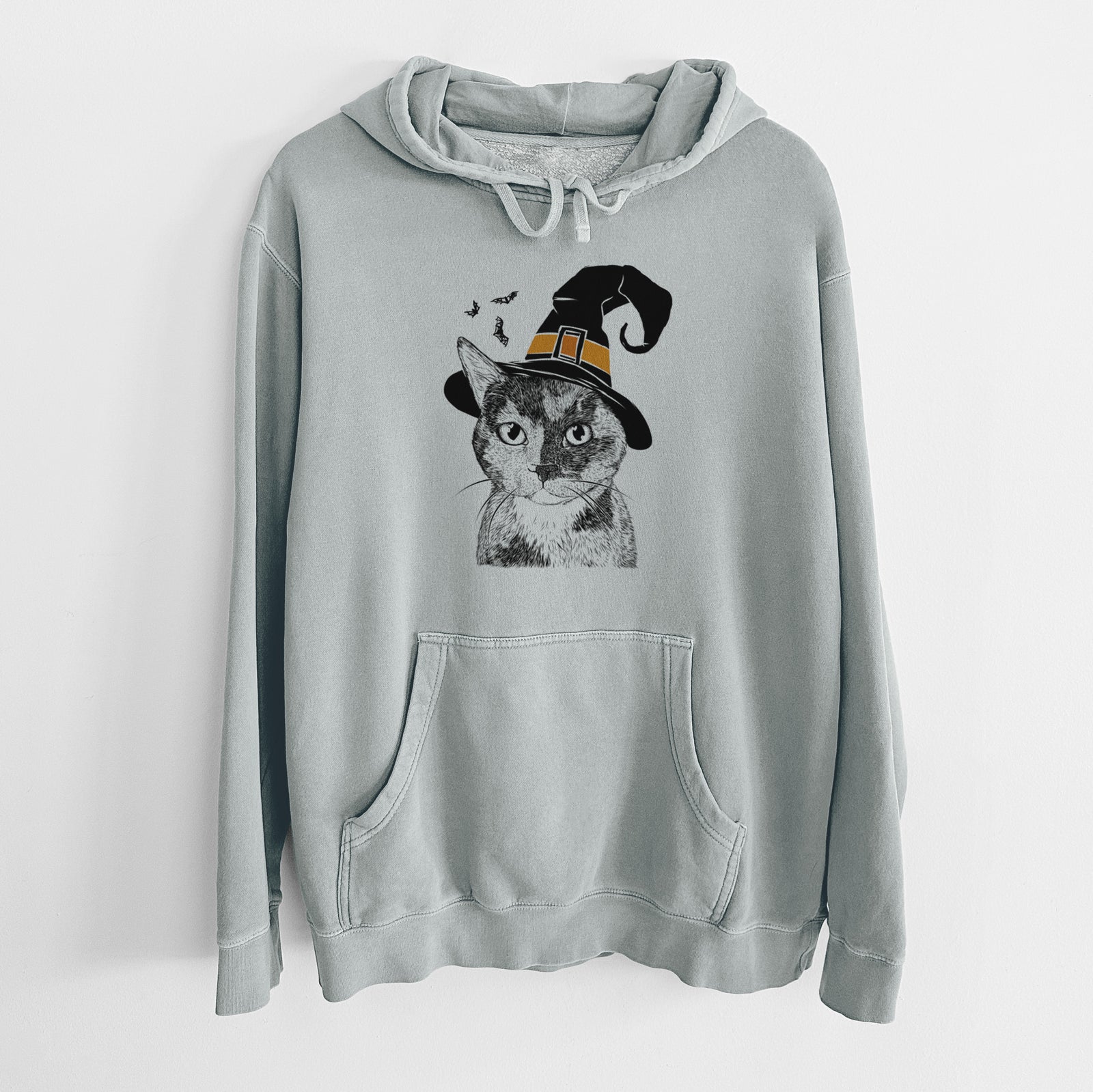 Hand-drawn sketch of Spooky Kitty the Tortoiseshell Cat wearing a witch hat on a Sage Unisex pigment dyed hoodie