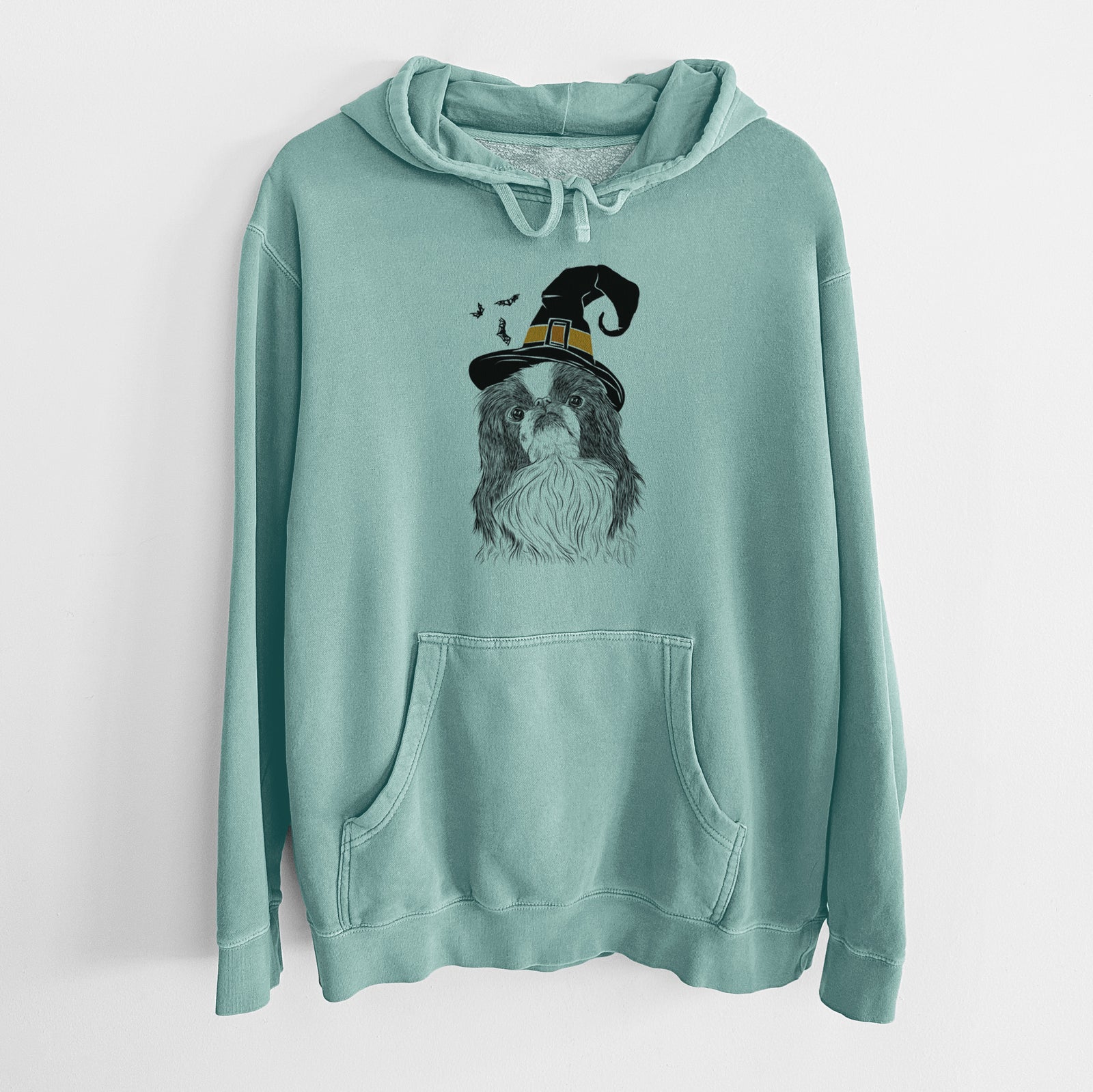 Hand-drawn sketch of Suki the Japanese Chin wearing a witch hat on a Mint Unisex pigment dyed hoodie
