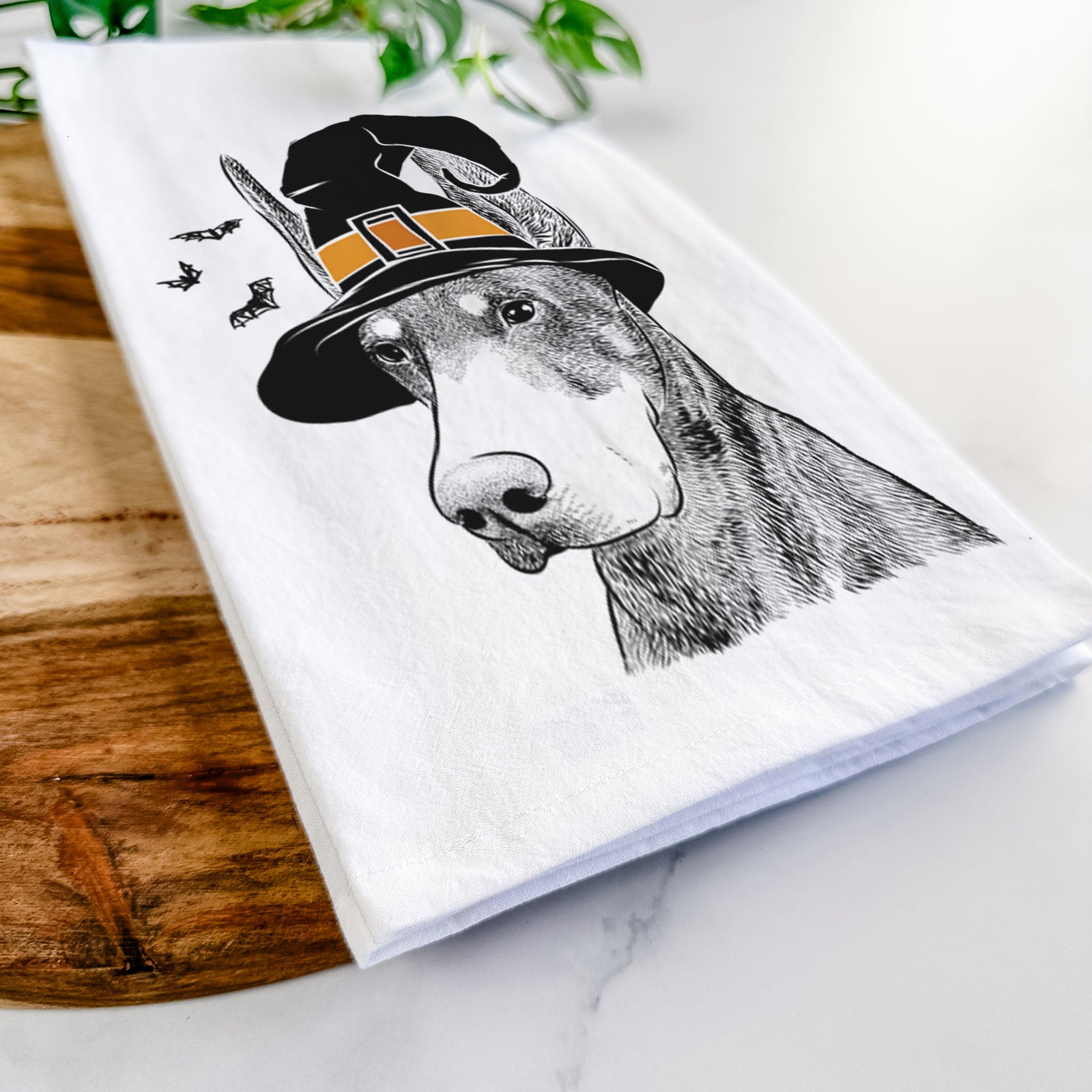 Hand-drawn sketch of Sunny the Doberman Pinscher wearing a witch hat on a tea towel