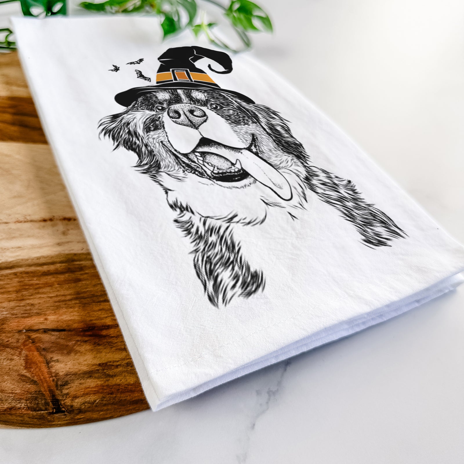 Hand-drawn sketch of Theo the Bernese Mountain Dog wearing a witch hat on a tea towel