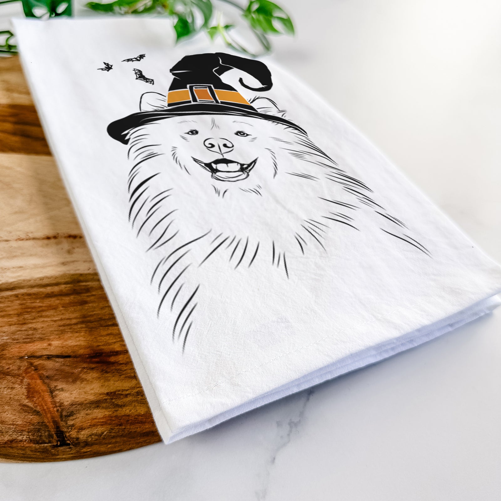 Hand-drawn sketch of Tillie the Samoyed wearing a witch hat on a tea towel