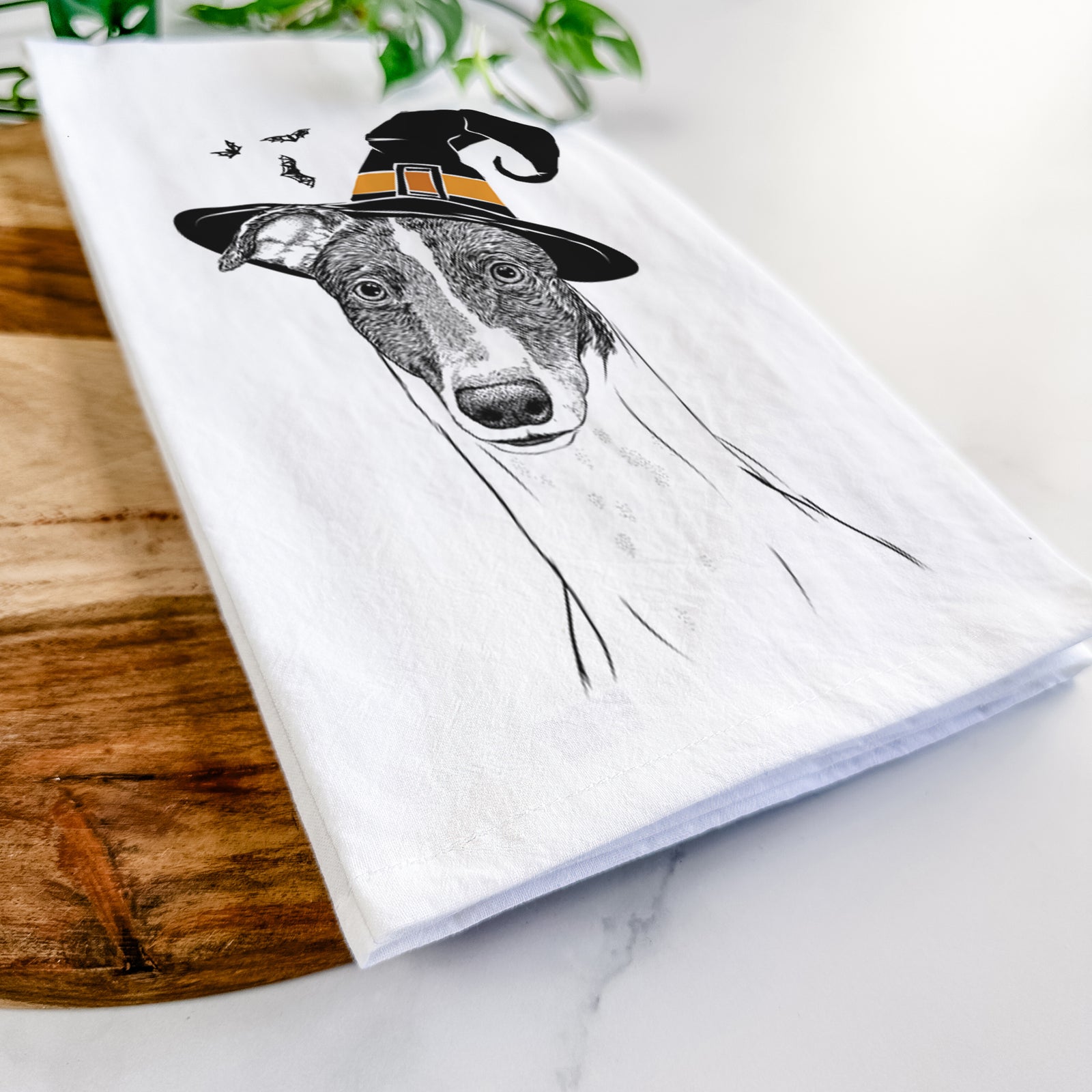 Hand-drawn sketch of Vyncent the Greyhound wearing a witch hat on a tea towel